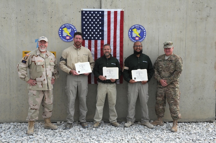 Col. Robert Ruch, commander, U.S. Army Corps of Engineers, Engineering and Support Center, Huntsville, right, and Fred Cartes, Task Force POWER project manager and contracting officer's representative, left, present certficates of achievement to Rafael Varela, Kevin Flynn and Shane Deek, EXP Federal for going above and beyond following an attack on Camp Integrity, Afghanistan in August. Abel Martinez and Sean McMurtrey also received certificates. Ruch presented the certificates during a site visit in October.