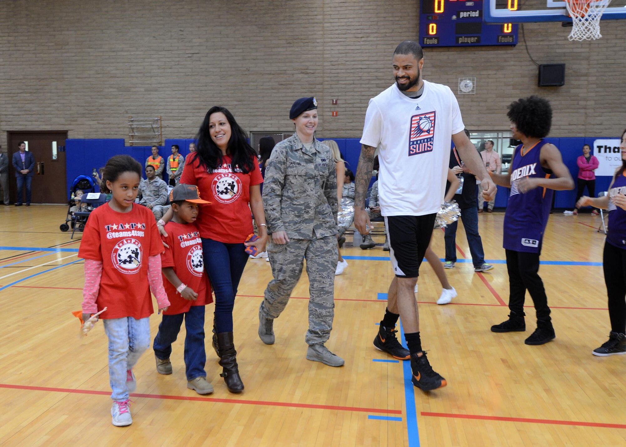 Tyson Chandler, Phoenix Suns center, walks with Senior Airman Destiny Sandoval, 56th Security Forces Squadron patrolman, and the Mark family into the Bryant Fitness Center. The players each escorted family members of fallen heroes before their practice demonstration.