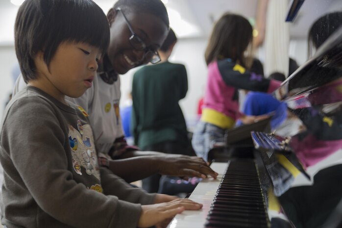 Cpl. Temeshia Morris, aviation supply specialist with Marine Aviation Logistics Squadron 12, plays piano during a Single Marine Program volunteer event with a Japanese orphan from Kaihoku-En Children’s Home in Houfu City, Japan, Nov. 14, 2015. The children interacted and built relationships with the 18 service members during the visit. This is approximately the 16th time in the last four years station service members volunteered their time and visited the children.