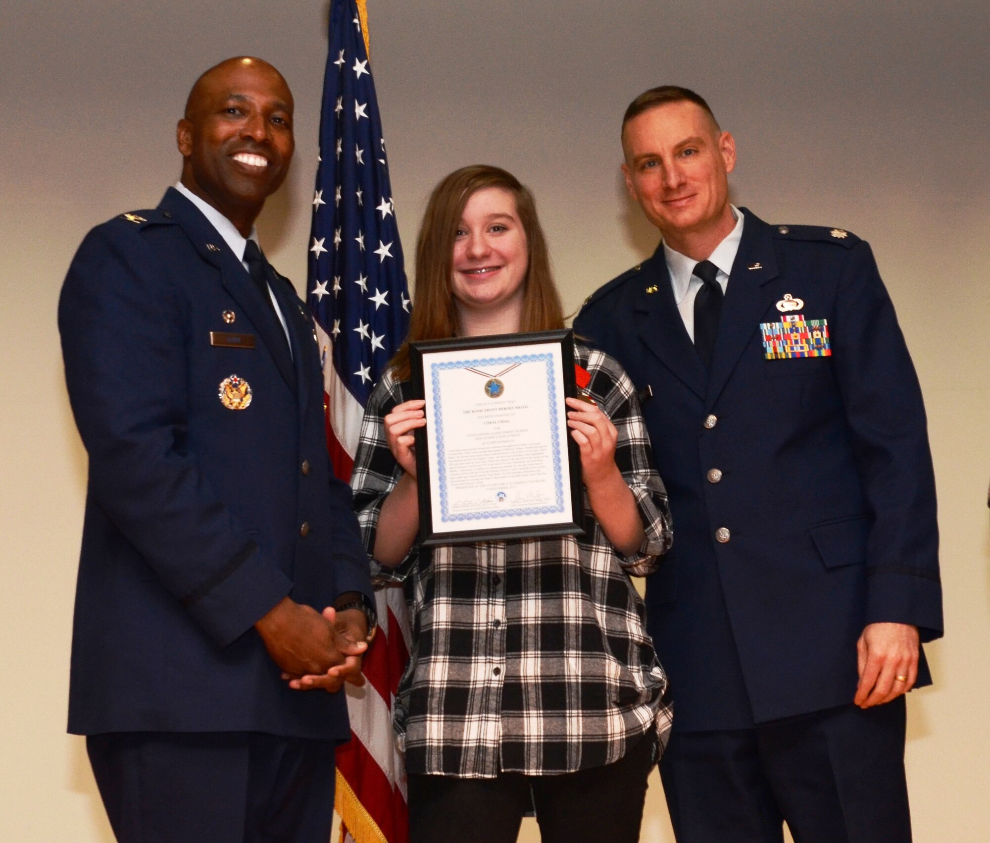 Coral Vidal (center) and her father, Lt. Col. Brus Vidal (right), the director of the U.S. Air Force Academy Public Affairs Office, stand with Col. Troy Dunn, 10th Air Base Wing commander, Nov. 14, 2015. Coral is one of several Academy children recognized as a Home Front Hero in a ceremony hosted by the Airman and Family Readiness Center. The program recognizes the sacrifices of military children during their parent's deployment. Vidal recently returned from an overseas deployment. (U.S. Air Force photo/Tech. Sgt. Heather Stanton)   
