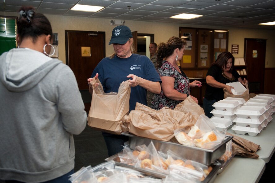 Volunteers pack plates of food during a drive-thru family dinner, Nov. 17, 2015, at Moody Air Force Base, Ga. The commissary donated the main course while the base chapel provided sides and desserts to feed families of service members on a remote tour, families of deployed service members and participants of the Exceptional Family Member Program. (U.S. Air Force photo by Airman 1st Class Kathleen D. Bryant/Released)
