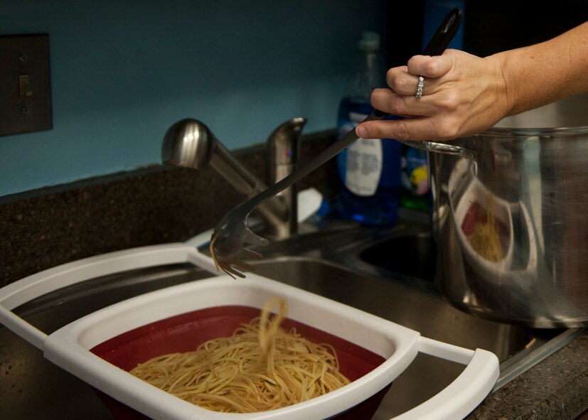 A volunteer strains spaghetti for a drive-thru family dinner at the base chapel, Nov. 17, 2015, at Moody Air Force Base, Ga. During the event, approximately 200 meals were prepared for deployed and remote assignment families, as well as Exceptional Family Member Program participants. (U.S. Air Force photo by Airman 1st Class Kathleen D. Bryant/Released)
