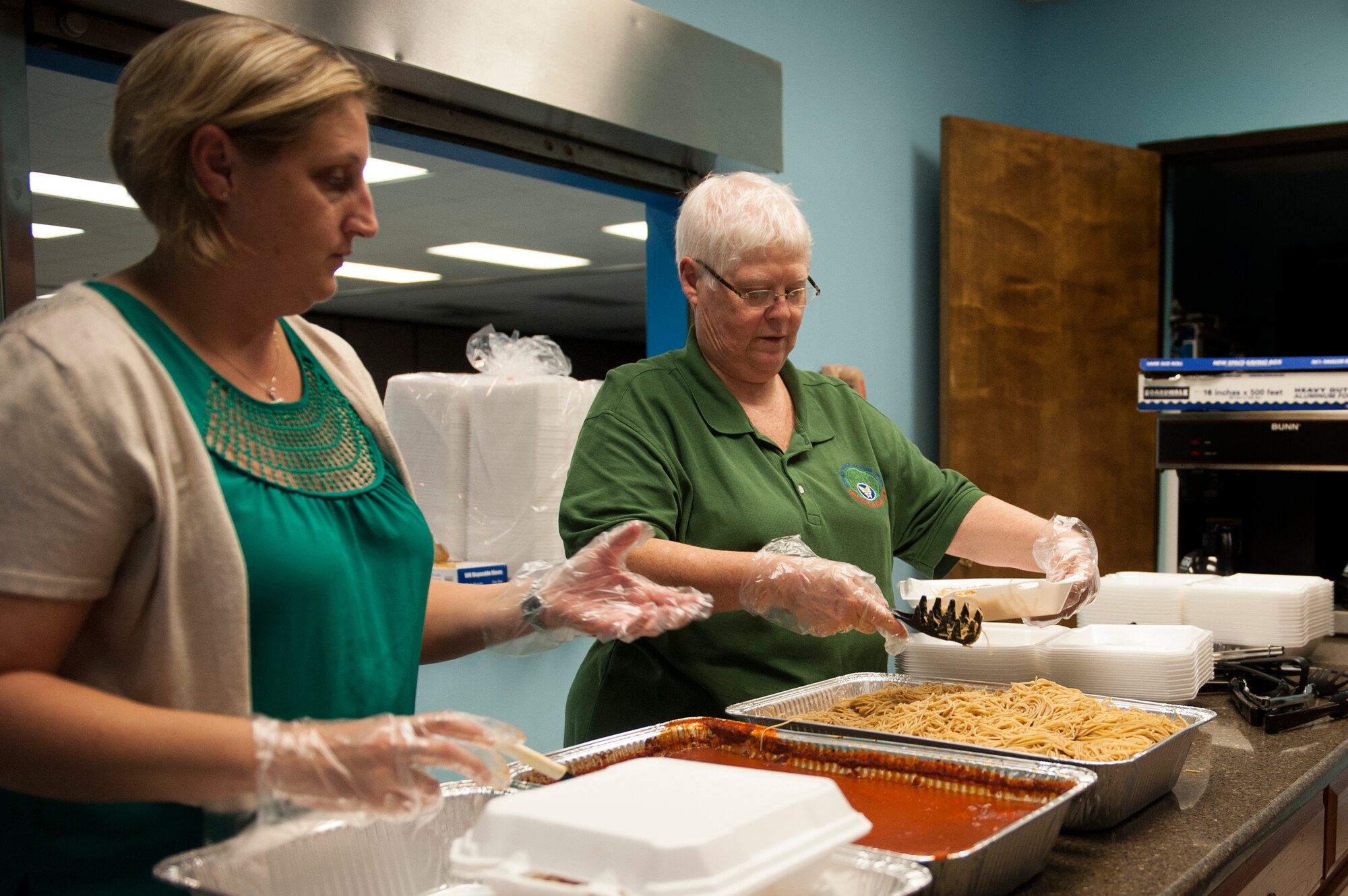 Peggy Beauvais, 23d Force Support Squadron Airman and Family Readiness Center chief, right, and Andrea Matthes, a local volunteer, make plates for a drive-thru family dinner, Nov. 17, 2015, at Moody Air Force Base, Ga. Deployed and remote assignment families, as well as Exceptional Family Member Program participants, drove up to the chapel and received meals for their families. (U.S. Air Force photo by Airman 1st Class Kathleen D. Bryant/Released)
