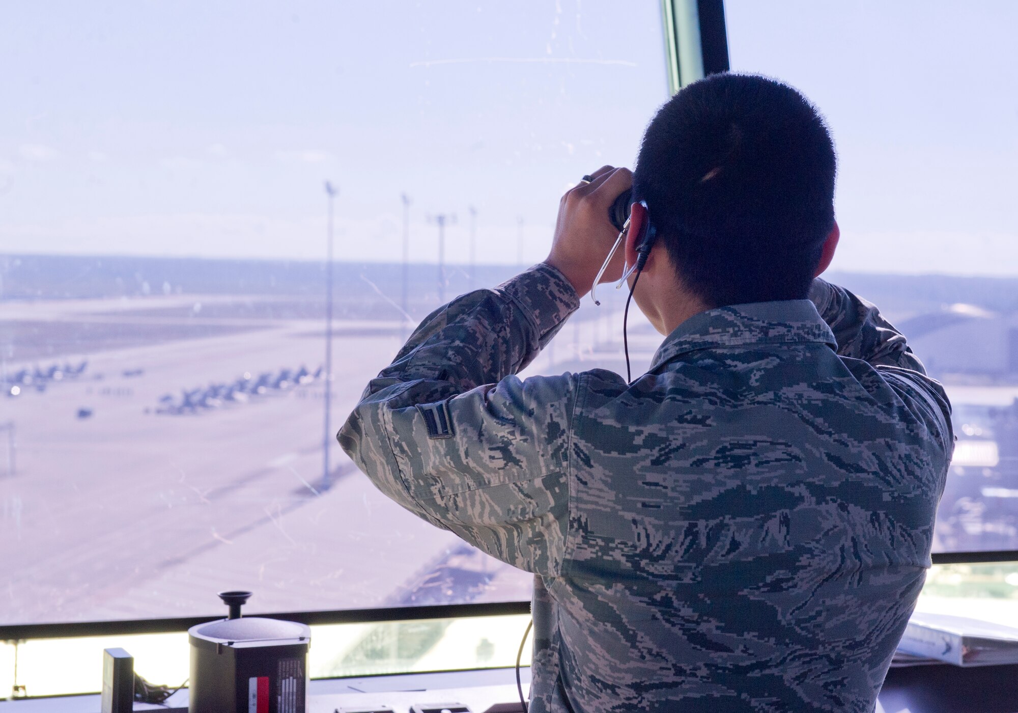 Airman 1st Class Alexander Infante, 325th Operations Support Squadron air traffic control apprentice, looks through binoculars at the flight line Nov. 12 at the Air Traffic Control Tower. The controllers ensure aircraft are able to take off and land safely and efficiently. (U.S. Air Force photo by Senior Airman Alex Fox Echols III/Released)