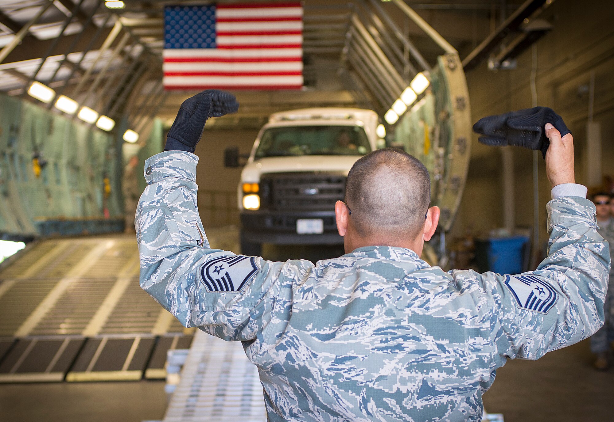Master Sgt. Jesse Lopez, 733rd Training Squadron senior NCO in charge, directs a truck down the ramp of a C-5 trainer aircraft at the 433rd Airlift Wing Nov.18, 2015 at Joint Base San Antonio-Lackland, Texas. Texas National Guard members from the 836th Engineer Company, practiced securing loads on a C-5 trainer aircraft, practiced making their equipment airworthy, and completed joint inspections during the training evolution. (U.S. Air Force photo by Benjamin Faske) (released)