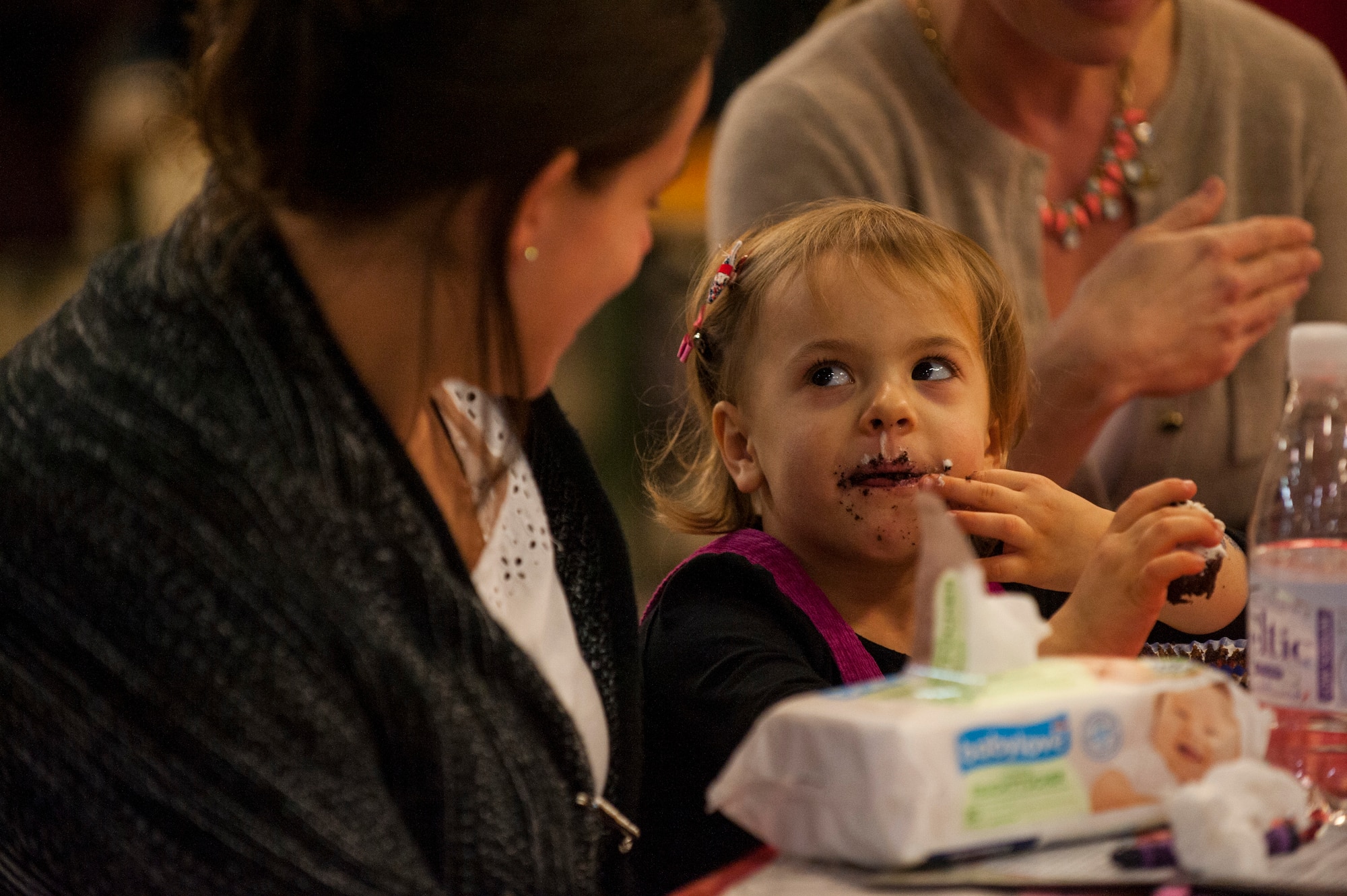 A child looks at her mom while she eats a cupcake during the Deployed Family Member Thanksgiving dinner inside Fire Station 1 at Spangdahlem Air Base, Germany, Nov. 18, 2015. The Airman and Family Readiness Center hosted this year’s Thanksgiving dinner.(U.S. Air Force photo by Senior Airman Rusty Frank/Released)
