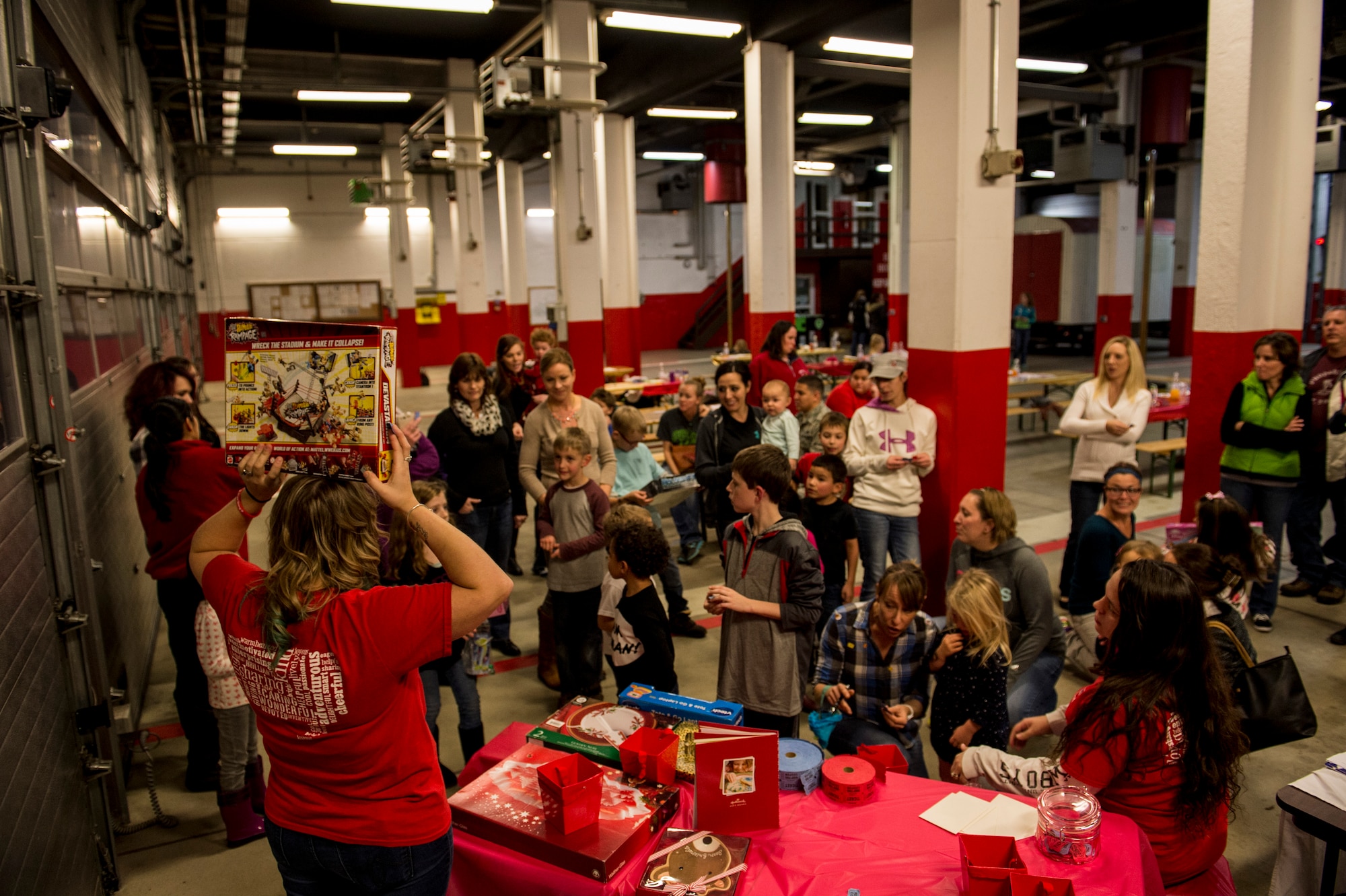 A Spangdahlem Spouses and Enlisted Members Club member, hands out gifts during the Deployed Family Member Thanksgiving dinner inside Fire Station 1 at Spangdahlem Air Base, Germany, Nov. 18, 2015. Families participated in a raffle, interacted with Santa Claus, and ate dinner during the event.  (U.S. Air Force photo by Senior Airman Rusty Frank/Released)