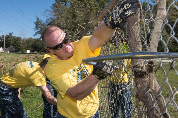 Senior Chief Petty Officer Justin Thompson, an instructor at the Navy Nuclear Power Training Command at Joint Base Charleston – NWS, S.C., helps remove an in-grown tree from the fence at the Young Men’s Christian Association in Summerville, S.C., on Nov. 13, 2015. Thompson and other JB Charleston members were at the YMCA and several other locations to participate in the Day of Caring event. (U.S. Air Force photo/Airman 1st Class Thomas T. Charlton)