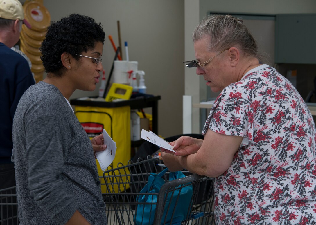 U.S. Air Force Staff Sgt. Heydii, a censor planner program manager shift lead assigned to the 497th Operation Support Squadron, explains Operation Warmheart to a Commissary patron at Langley Air Force Base, Va., Nov. 16, 2015.  The majority of the distributions Operation Warmheart makes for the Joint Base Langley-Eustis community is during the holiday seasons. (U.S. Air Force photo by Staff Sgt. J.D. Strong II)