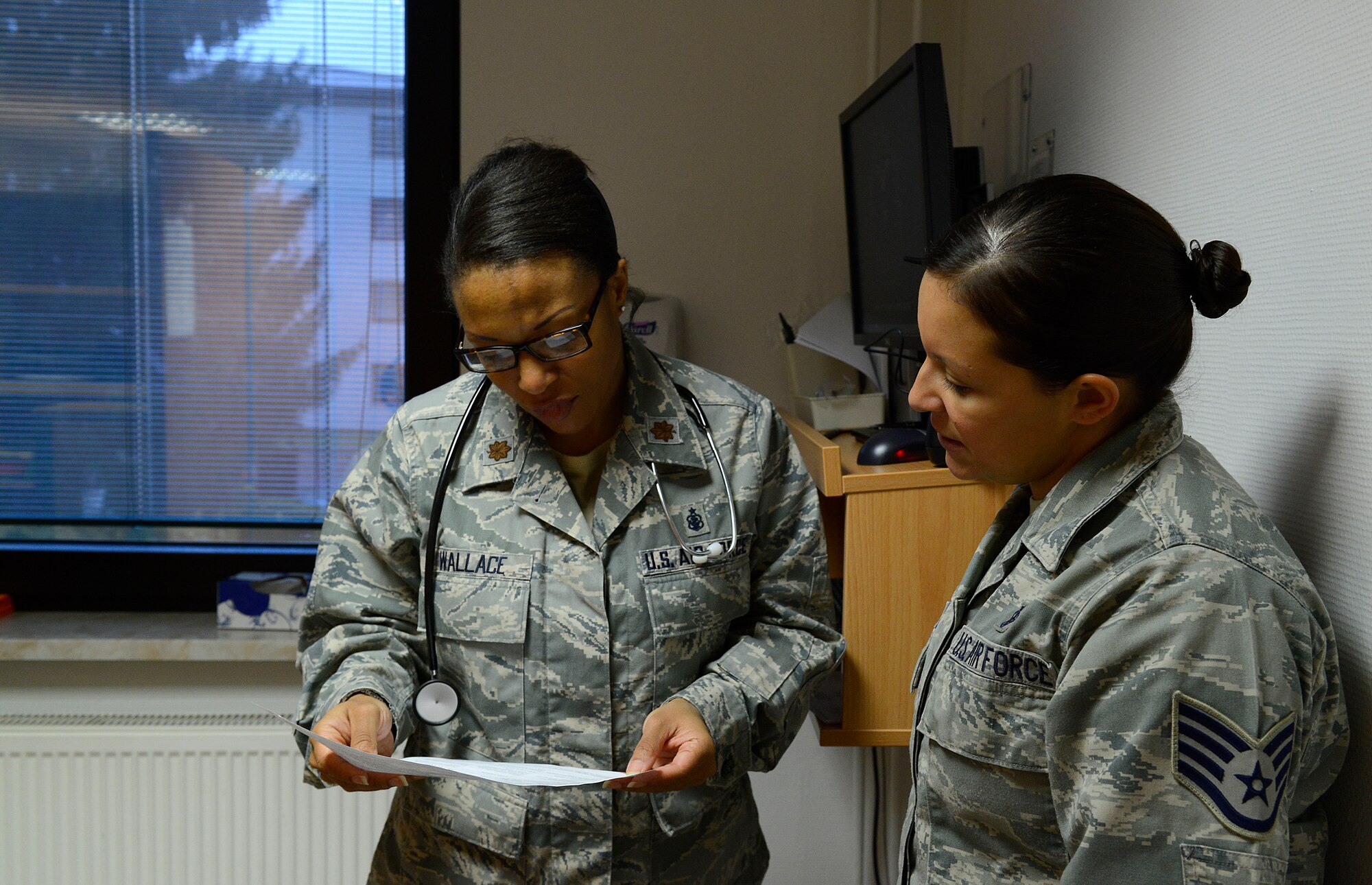 Staff Sgt. Megan Cotter, 86th Medical Operations Squadron NCO in charge of ambulance services, tells Maj. Courtney Wallace, Family Health Clinic clinical nurse, about the symptoms of a patient being seen at the Cold and Allergy Clinic at Ramstein Air Base, Germany, Nov. 4, 2015. The clinic was opened to help relieve the increased volume of patients brought to the Family Health Clinic suffering from symptoms associated with the winter and spring seasons. (U.S. Air Force photo/Airman 1st Class Tryphena Mayhugh)