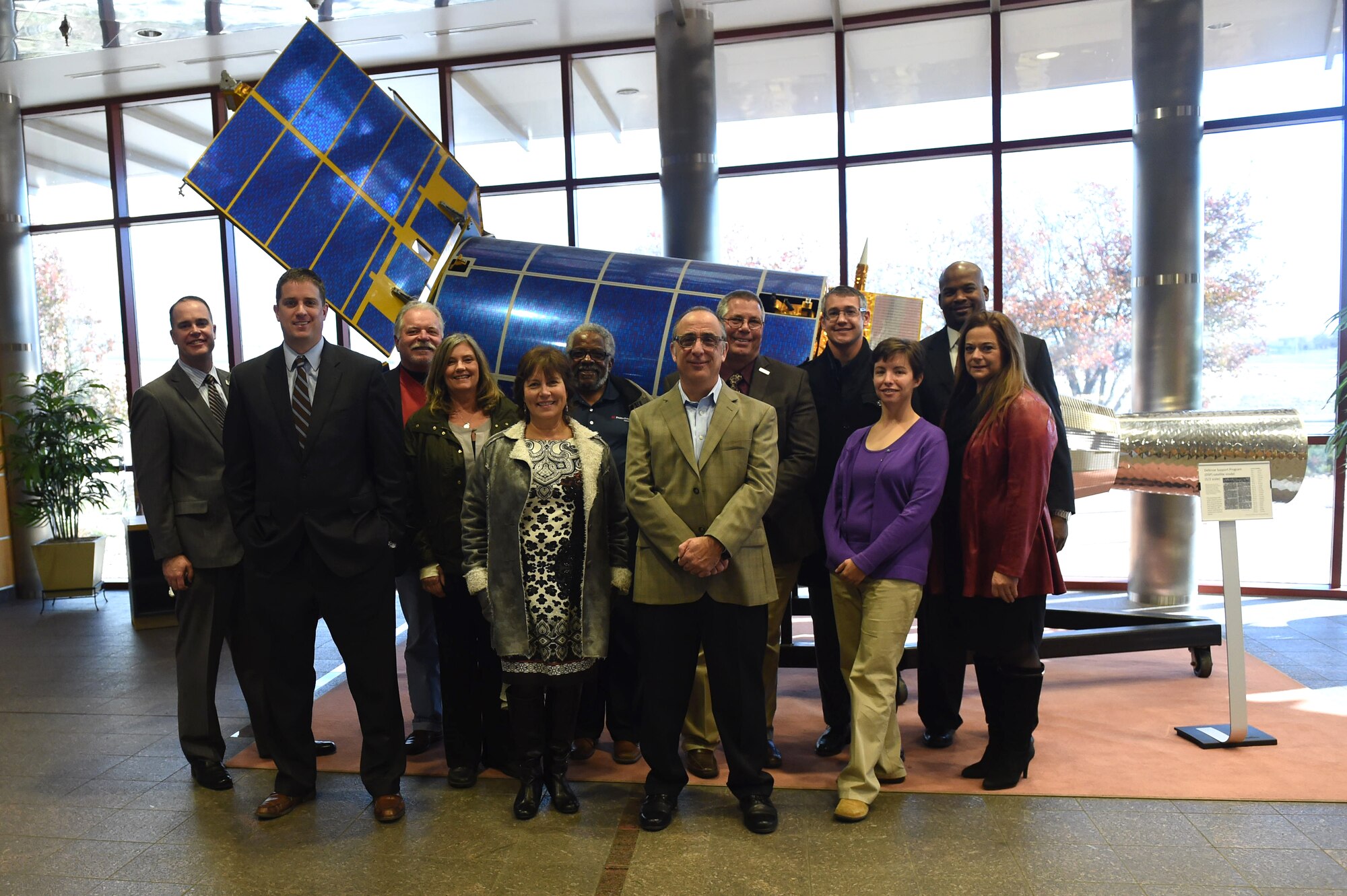 Aurora Defense Council members stand in front of a Defense Support Program spacecraft model in the 460th Operations Group Mission Control Station Nov. 19, 2015, on Buckley Air Force Base, Colo. The council members had a chance to tour the MCS lobby and get an inside look at a radome as part of a tour after the 460th Space Wing hosted the Aurora Defense Council meeting. (U.S. Air Force photo by Airman 1st Class Samantha Meadors/Released)