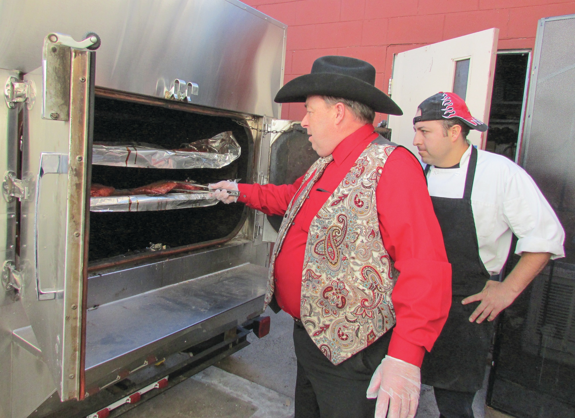 Robert Vick, who operates Thunderbird Dining Hall on Kirtland Air Force Base and Vick’s Vittles on Central Avenue, handles ribs in the smoker at Vick’s Vittles as his chef and “right arm,” Emeterio Chavez-Arteaga, looks on. (Photo by Argen Duncan)