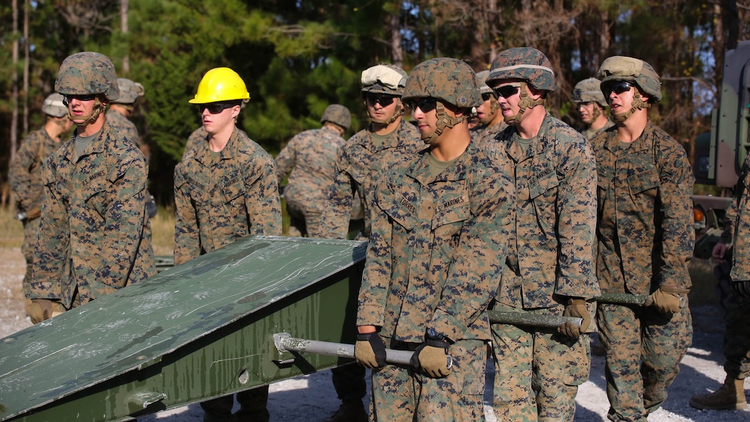 Marine students attending the 8th Engineer Support Battalion Medium Girder Bridge Master’s Course lift a bridge part during a field exercise at Marine Corps Base Camp Lejeune, North Carolina, Nov. 18, 2015. The building blocks for the bridge weigh between 400 and 600 pounds. When a bridge is complete, it is capable of holding the weight of an M1 Abrams tank, or approximately 60 tons. 
