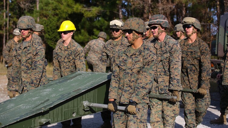 Marine students attending the 8th Engineer Support Battalion Medium Girder Bridge Master’s Course lift a bridge part during a field exercise at Marine Corps Base Camp Lejeune, North Carolina, Nov. 18, 2015. The building blocks for the bridge weigh between 400 and 600 pounds. When a bridge is complete, it is capable of holding the weight of an M1 Abrams tank, or approximately 60 tons. 
