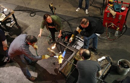 Participants and instructors of the Hot Shop Heroes program work on the "Tree of Life," representing the growth of the class from the roots up, Nov. 8, 2015, at the Museum of Glass in Tacoma, Wash. The Hot Shop Heroes program teaches soldiers glass art as a way to heal from the trauma of war. (U.S. Army photo by Pfc. Sarah K. Anwar)