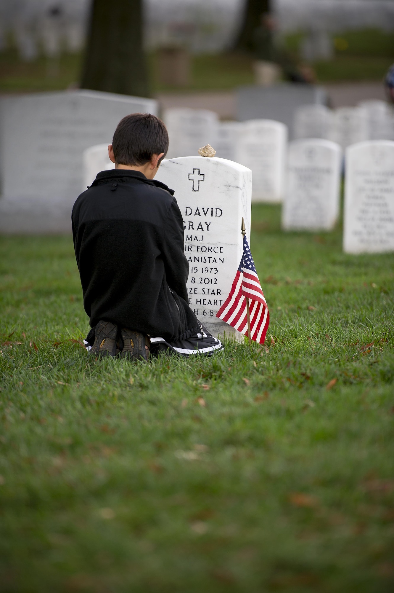 Garrett Gray, 9, kneels in front of the headstone for his father, Maj. David Gray, at Arlington National Cemetery, Va., Nov. 11, 2015. His father was killed in action Aug. 8, 2012, during a deployment to Afghanistan. David’s wife, Heather, and her three children moved from Colorado, where David was stationed at Fort Carson, earlier this year for the first time since his death. (U.S. Air Force photo/Staff Sgt. Christopher Gross)