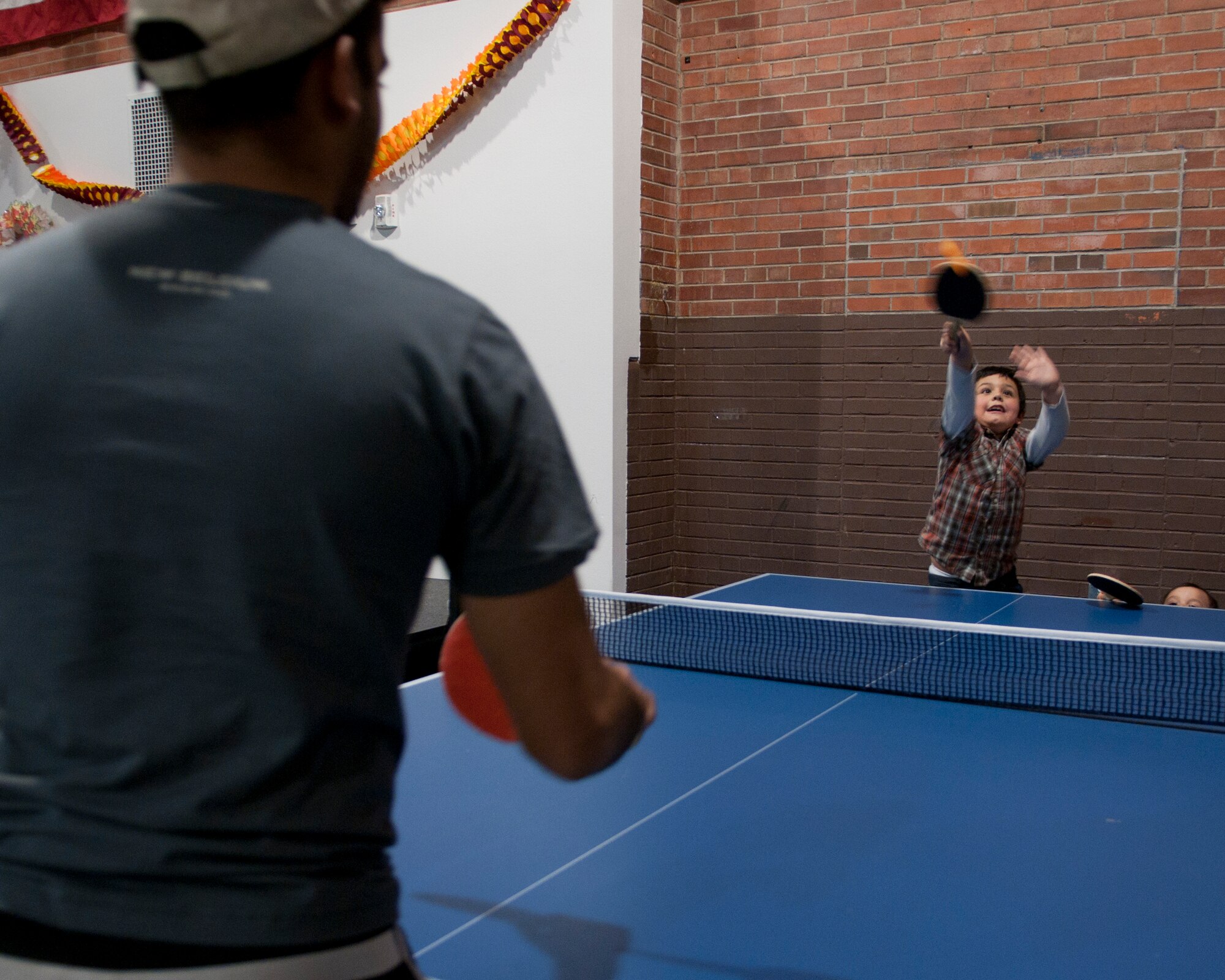 Carlos Caldera Jr., 7, son of 1st Lt. Carlos Caldera Sr., 90th Medical Operations Squadron physician assistant, hits a ping pong ball toward 2nd Lt. Octavio Otero, 90th Security Forces Squadron flight commander, in the Fall Hall Community Center Nov. 19, 2015, during the base chapel’s Thanksgiving dinner event. Many activities were offered at the event which gave Airmen an opportunity to interact with various families on base and form relationships for the holiday season. (U.S. Air Force photo by Airman 1st Class Malcolm Mayfield)