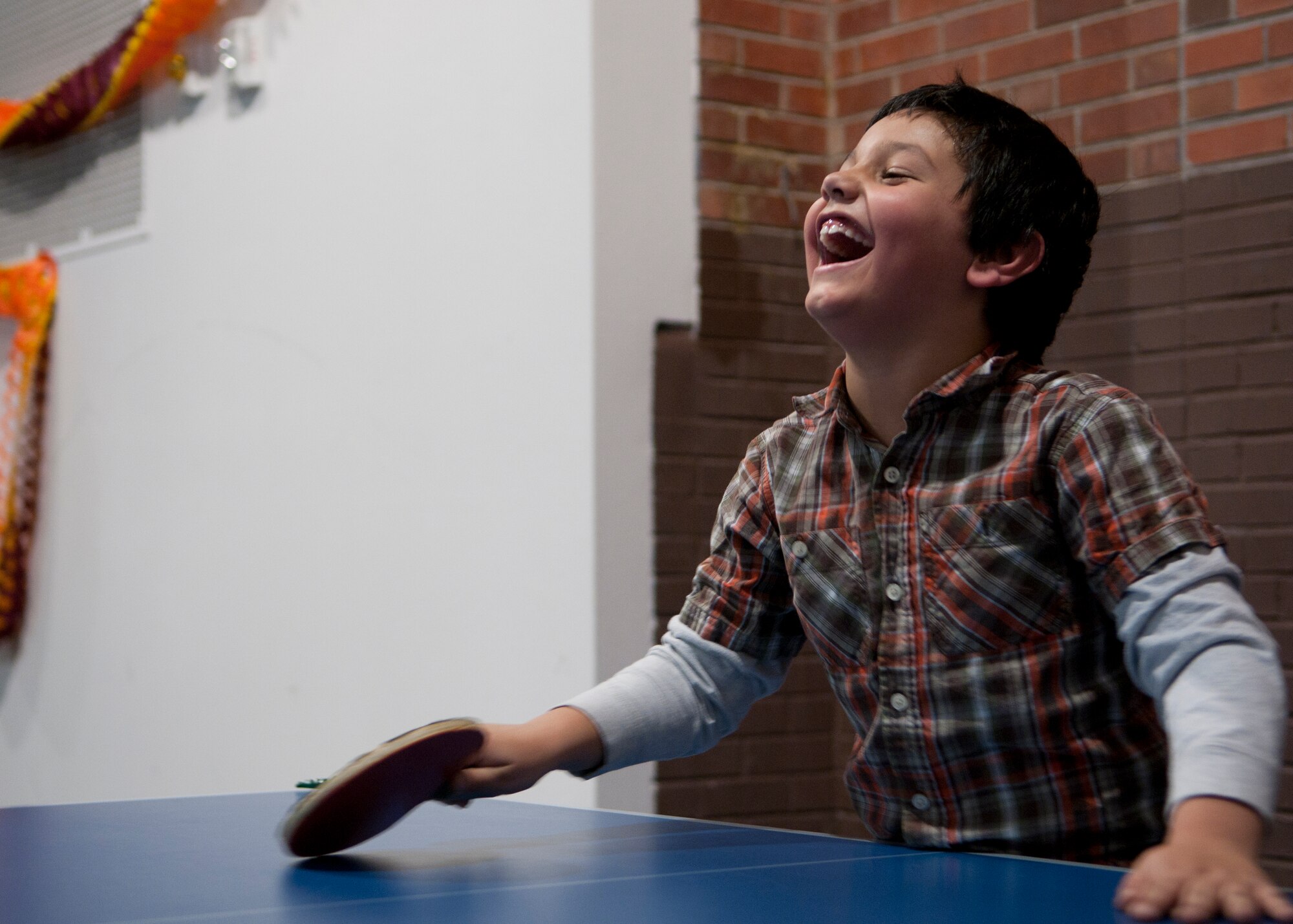 Carlos Caldera Jr., 7, son of 1st Lt. Carlos Caldera Sr., 90th Medical Operations Squadron physician assistant, plays a game of ping pong with others in the Fall Hall Community Center Nov. 19, 2015, during the base chapel’s Thanksgiving dinner event. Families within the chapel community, which consists of people from the traditional, Catholic and contemporary services, gathered with Airmen to celebrate Thanksgiving early. (U.S. Air Force photo by Airman 1st Class Malcolm Mayfield)