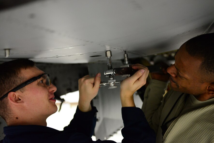 Tech. Sgt. Justin Archer and Airman 1st Class Cody Veloff, 51st Maintenance Squadron phase dock crew chiefs, work together to remove screws from a panel on the belly of an A-10 Thunderbolt II during a routine phase inspection at Osan Air Base, Republic of Korea, Nov. 16, 2015. Panel removal is the first step in the in-depth inspection and preventive maintenance regiment the airframe must undergo after every 500 flight hours. (U.S. Air Force photo/Staff Sgt. Amber Grimm)