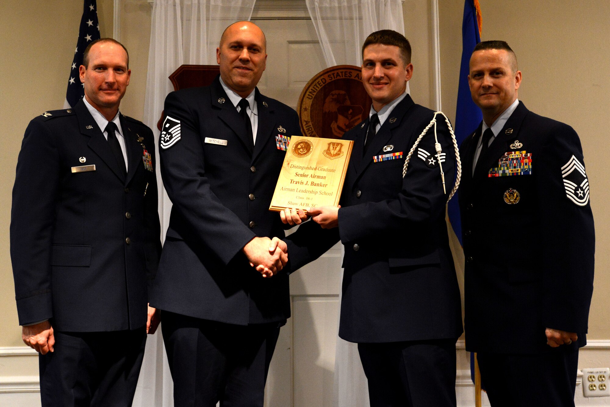 U.S. Air Force Senior Airman Travis Banker, 3rd Intelligence Squadron, receives a distinguished graduate award for the Senior Master Sgt. David B. Reid Airman Leadership School Class 16-1 from Master Sgt. Jeremy Mitchell, 20th Equipment Maintenance Squadron first sergeant, at Shaw Air Force Base, S.C., Nov. 20, 2015. The distinguished graduate awards are given to the top 10 percent of the class for total point accumulation. (U.S. Air Force photo by Airman 1st Class Kelsey Tucker)