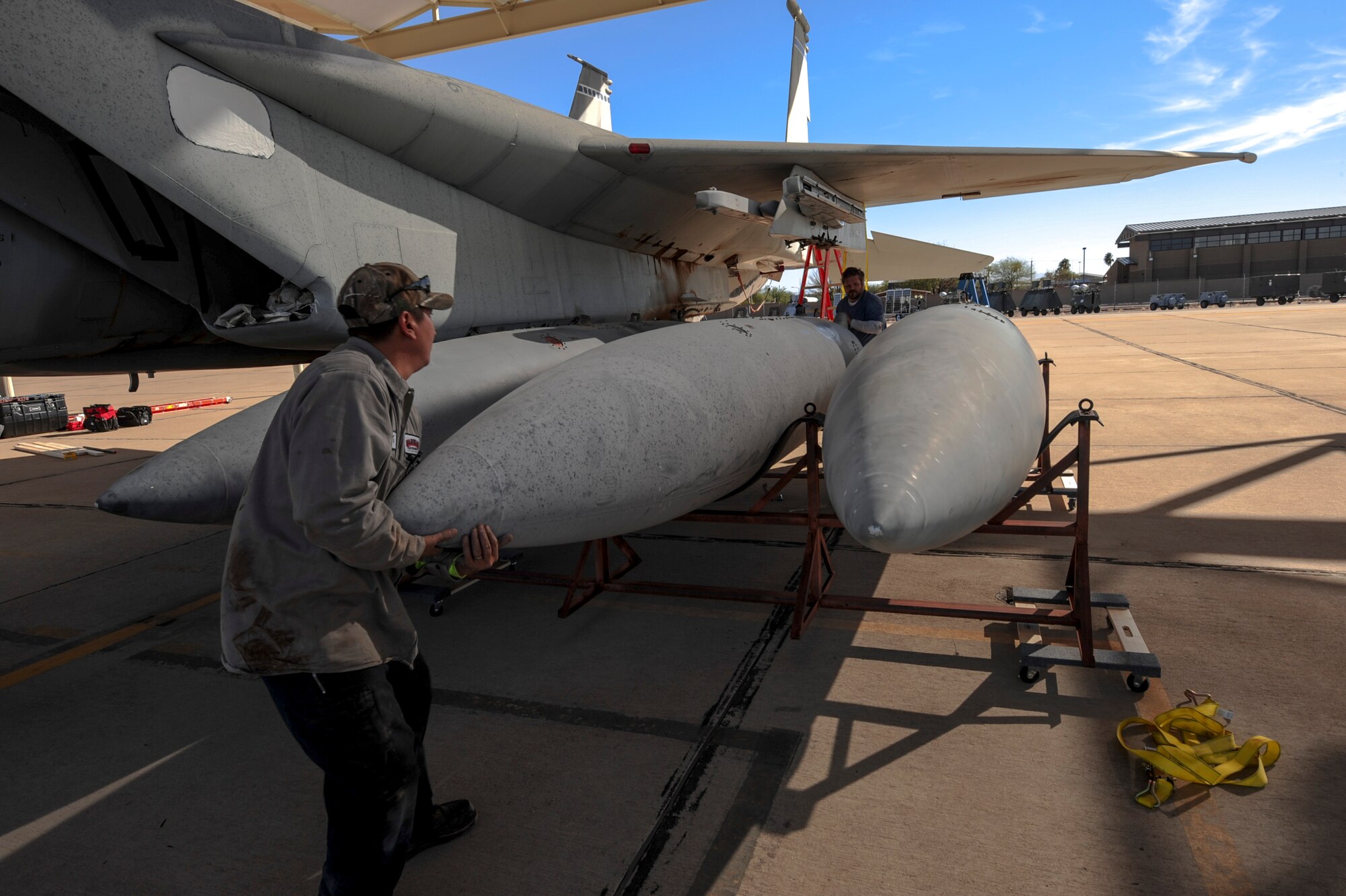 David Williamson, chief project manager, and Tony Martinez, crane mechanic, move a fuel tank from an F-15A Eagle on the flight line at Davis-Monthan Air Force Base, Ariz., Nov. 17, 2015. A team of contractors took five days to completely disassemble the F-15A Eagle and load it onto two flatbed trucks to be shipped to Joint Base Lewis-McChord, Wash., for display. The entire project is estimated to take approximately eight months from the planning stage to finish. (U.S. Air Force photo by Airman Basic Nathan H. Barbour/Released)