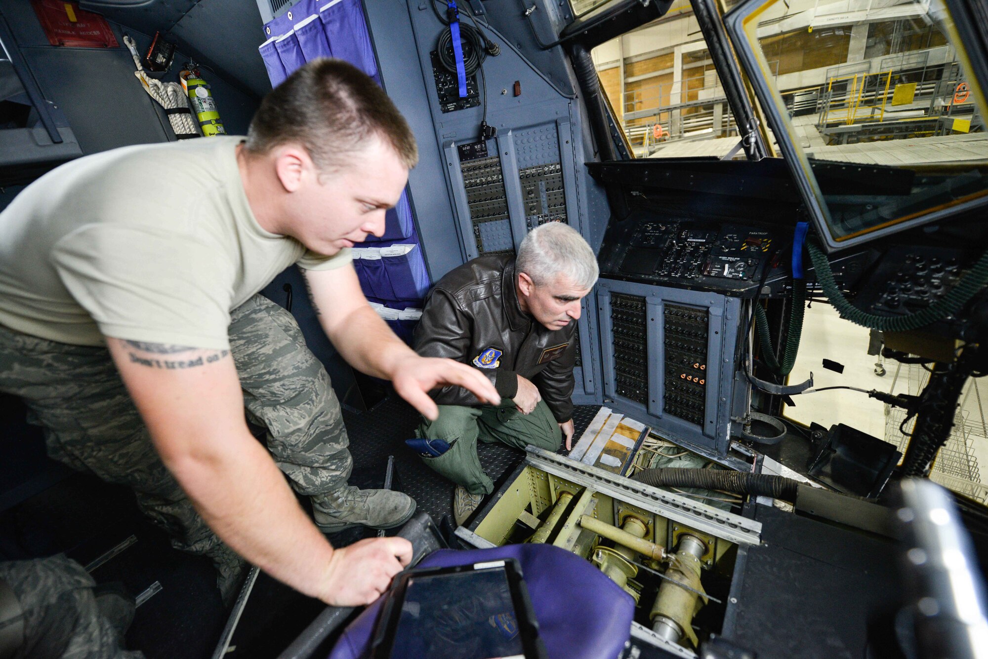 Staff Sgt. Jacob Haefemeyer, 934th Maintenance Squadron, shows Col. Keith Wesley, 934th Airlift Wing commander, some of the control cables revealed after removal of the seats in the C-130 flight deck. The seats were removed and refurbished as part of the flight deck maintenance program. (Air Force Photo/Paul Zadach)