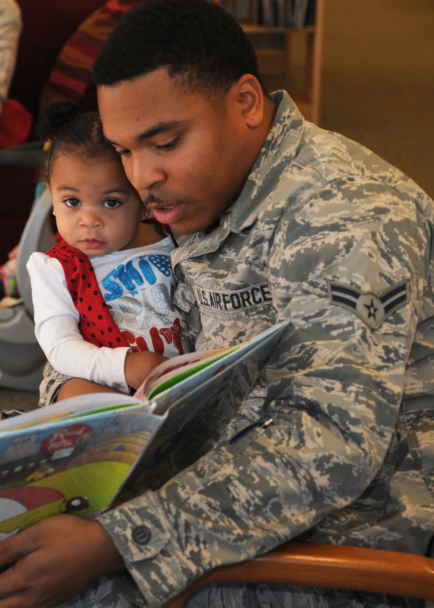 Airman 1st Class Terrell Jackson, 28th Logistics Readiness Squadron pest management journeyman, reads to his daughter during the Holbrook Library’s Little Warriors Story Time program at Ellsworth Air Force Base, S.D., Nov. 12, 2015. The program which promotes child literacy is held every Thursday from 11 to 11:30 a.m. (U.S. Air Force photo by Airman Sadie Colbert/Released)
