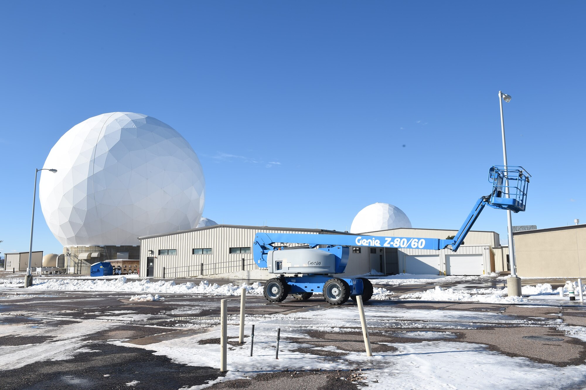 Bldg. 429 and 431 require a Team Buckley member to ride in a lift and clean the snow off the top of the roofs when the snow accumulation exceeds six inches, Nov. 18, 2015, on Buckley Air Force Base, Colo.  Currently, occupants of these two buildings must evacuate and find alternate duty locations when it snows. A proposal is in place to demolish these buildings and build the SBIRS Operations Facility, which is set to consolidate the work centers and offer permanent homes to the nearly 200 people who work in the existing facilities. (U.S. Air Force photo by Airman 1st Class Samantha Meadors/Released)