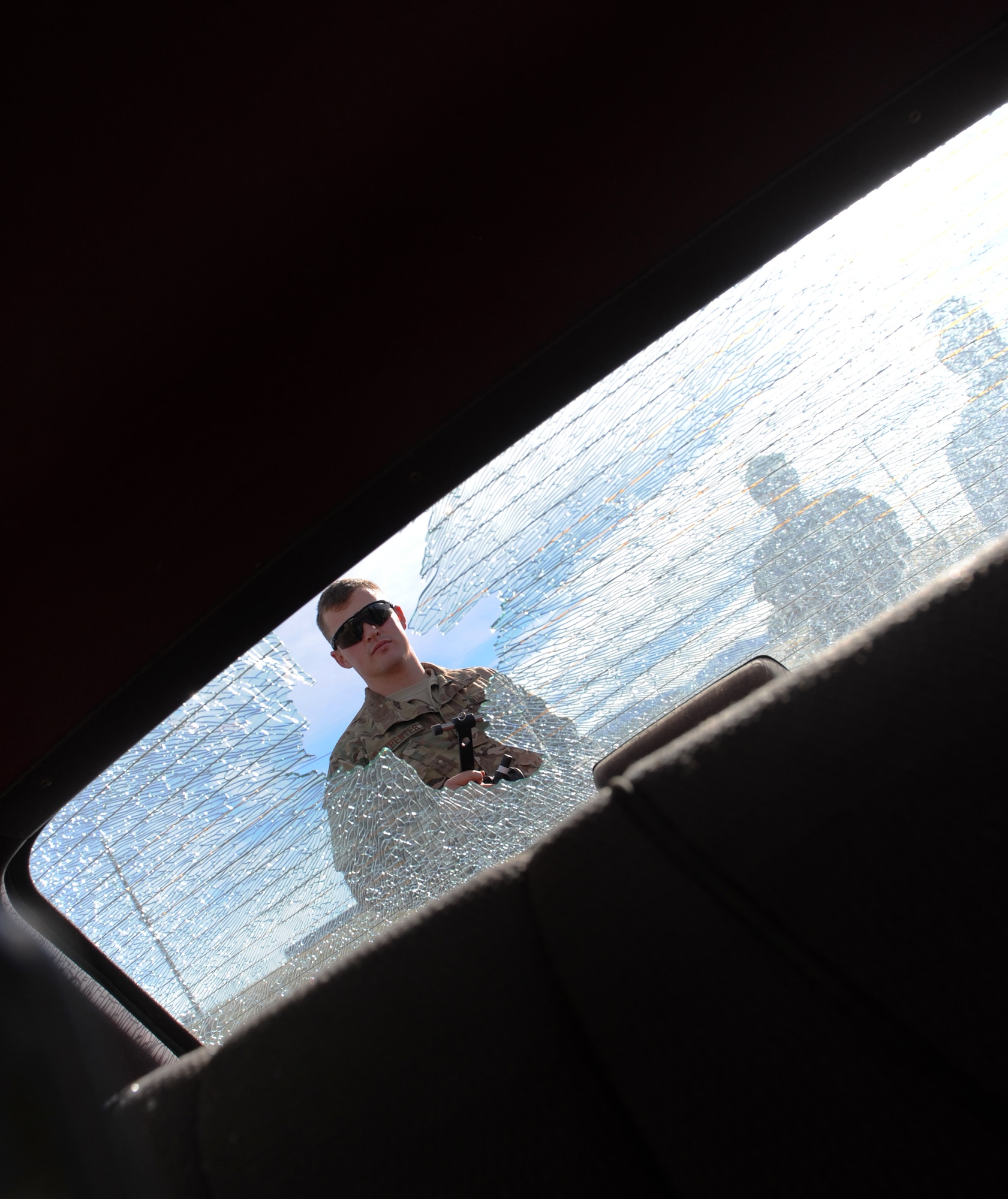 Senior Airman Zachary Carpenter, an Explosive Ordnance Technician with the 775th EOD Flight, peers into the back of a vehicle after breaking the back window using a long rope and a sharp lever.  Often, EOD technicians have to investigate suspicious vehicles, but need to gain access without lifting handles, opening doors or trunks, which may set off a booby trap. The hook-and-line allows them to gain an access point from a safe distance. Airmen from the flight participated in a week-long training event Nov. 2.-6, meant to pass on knowledge from veteran EOD techs to their younger counterparts. (U.S. Air Force photo/Micah Garbarino)