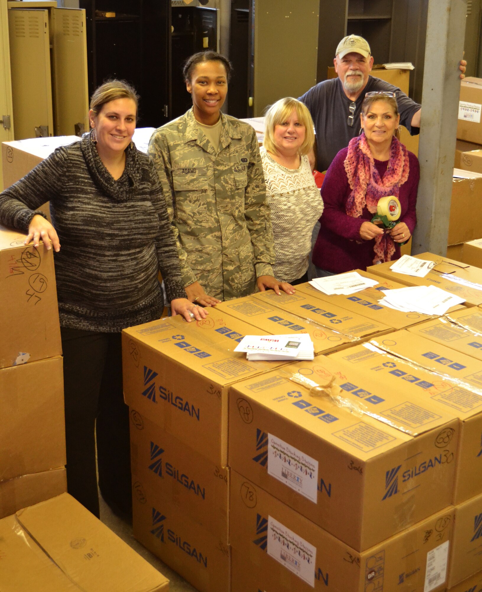 Members of the 111th Attack Wing, Liberty USO and volunteers stop working to take a photo with care packages they were preparing to send out at Horsham Air Guard Station, Pennslvania, Nov. 19, 2015. An estimated 5,000 package will be sent to deployed service members. (U.S. AIr National Guard photo by Tech. Sgt. Andria Allmond/Released)