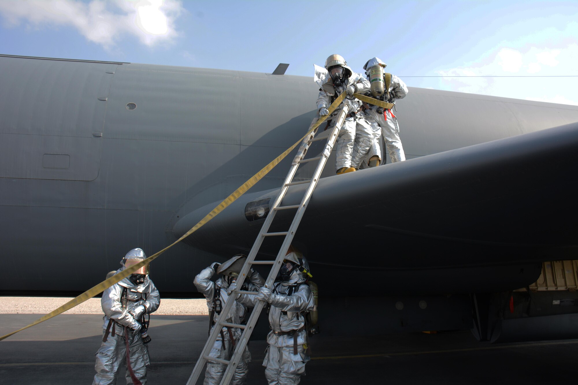 379th Civil Engineer Squadron firefighters work quickly to gain access to a KC-135 Stratotanker to put out a simulated fire and rescue an injured air crew member during a training exercise at Al Udeid Air Base, Qatar Nov. 20. Within minutes, several firefighters climbed on to the plane's left wing, entered the aircraft and pulled the injured air crew member to safety. Training exercises help first responders maintain their skillsets. (U.S. Air Force photo by Tech. Sgt. James Hodgman/Released)