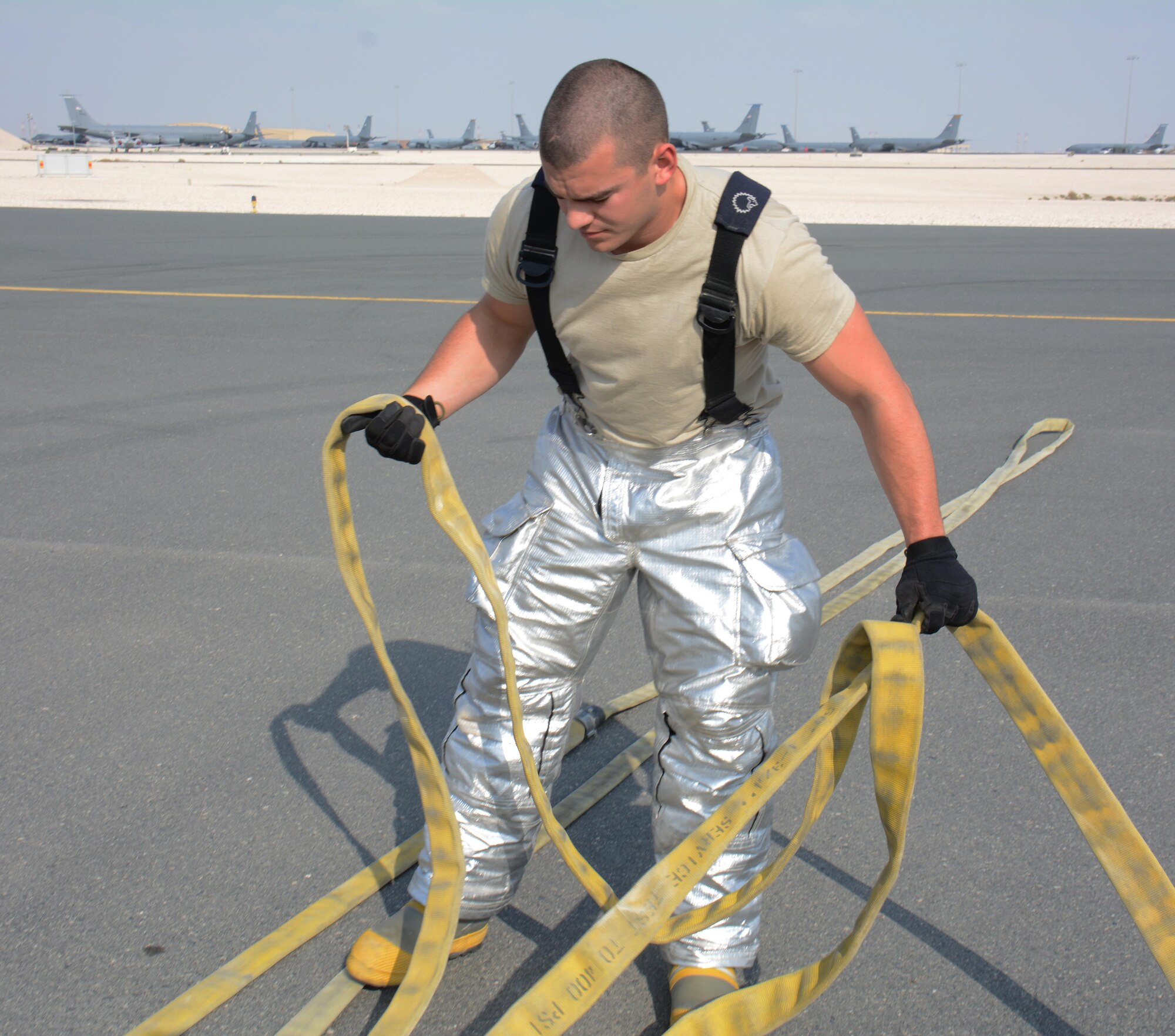 A 379th Civil Engineer Squadron firefighter works to put back a fire hose after a training exercise at Al Udeid Air Base, Qatar Nov. 20. The exercise featured a simulated fire on a KC-135 Stratotanker and required firefighters to rescue an injured air crew member. Within minutes, several firefighters climbed on to the plane's left wing, entered the aircraft and pulled the injured air crew member to safety. Training exercises help first responders maintain their skillsets. (U.S. Air Force photo by Tech. Sgt. James Hodgman/Released)