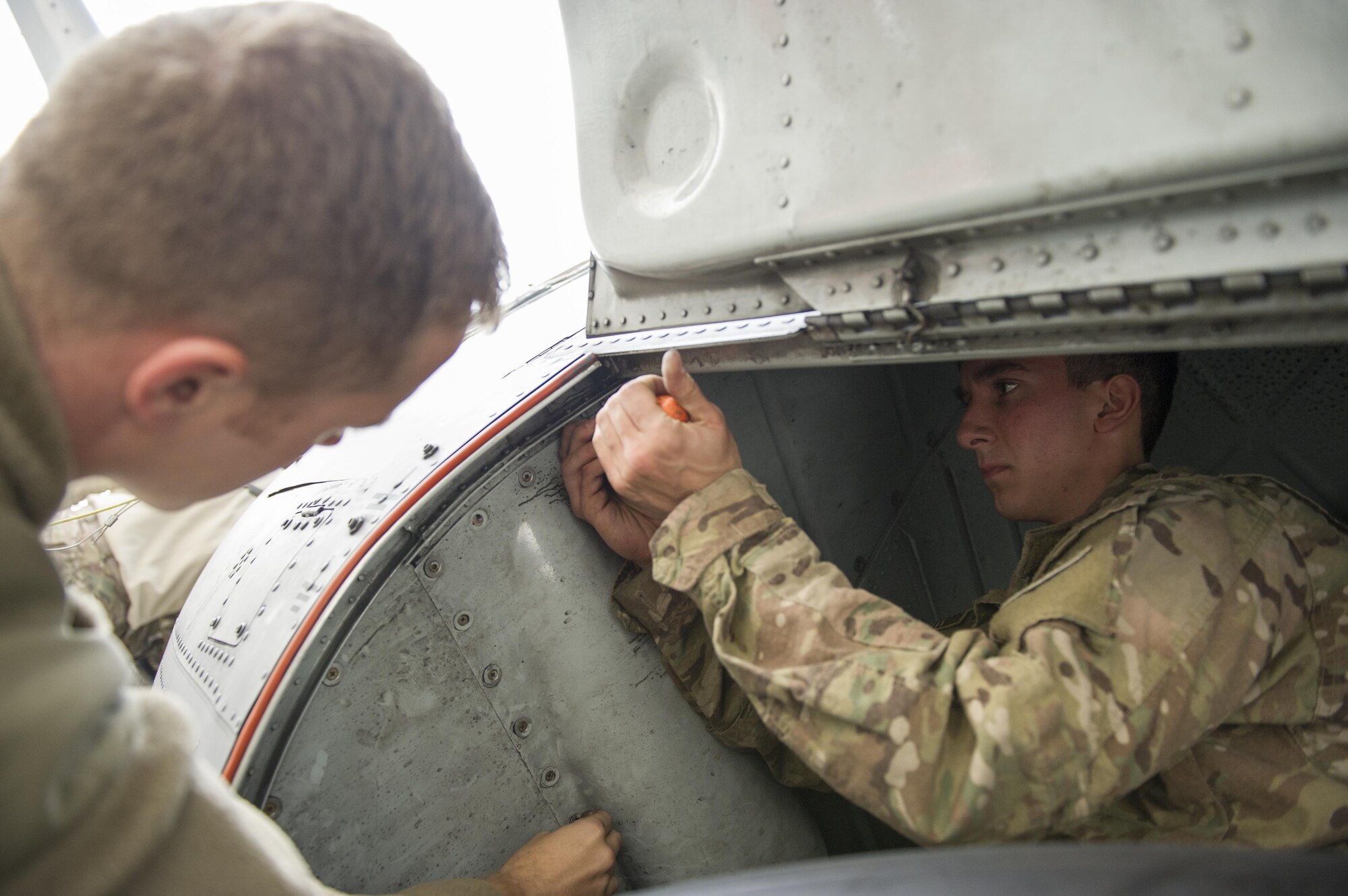 Senior Airman Dylan Shirey, right, 41st Expeditionary Aircraft Maintenance Unit aerospace repair crew chief, deployed from Davis-Monthan Air Force Base, Ariz., replaces a mud guard panel on an EC-130H Compass Call aircraft Nov. 19, 2015, at Bagram Airfield, Afghanistan. The Compass Call is an airborne tactical weapon system using a heavily modified version of the C-130 Hercules airframe. (U.S. Air Force photo by Tech. Sgt. Robert Cloys/Released)