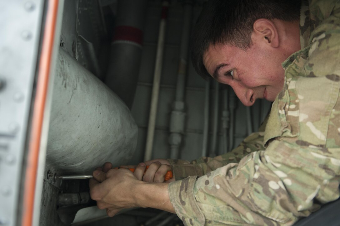 Senior Airman Dylan Shirey, 41st Expeditionary Aircraft Maintenance Unit aerospace repair crew chief, deployed from Davis-Monthan Air Force Base, Ariz., replaces a mud guard panel on an EC-130H Compass Call after repairing a refuel manifold Nov. 19, 2015, at Bagram Airfield, Afghanistan. The Compass Call is an airborne tactical weapon system using a heavily modified version of the C-130 Hercules airframe. (U.S. Air Force photo by Tech. Sgt. Robert Cloys/Released)