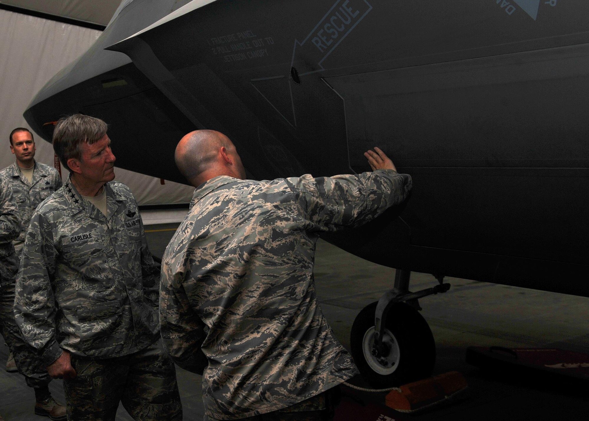 Maj. Samuel, 380th Air Expeditionary Maintenance Squadron commander, discusses the specifications and texture of an F-22A Raptor with Gen. Hawk Carlisle, commander of Air Combatant Command, in a facility at an undisclosed location in Southwest Asia, Oct. 19, 2015. Carlisle's visit was part of annual tour of the Air Force Central Command area of responsibility. (U.S. Air Force photo by Staff Sgt. Kentavist Brackin/Released)