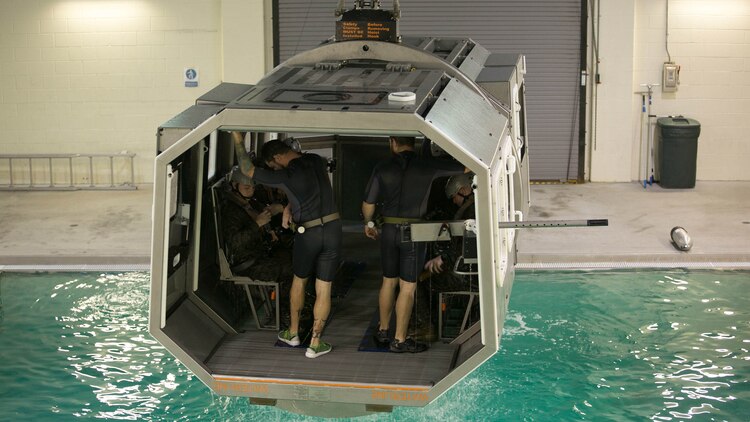 Marines with 2nd Low Altitude Air Defense Battalion and instructors with the Water Survival Training Facility prepare to be submerged in a pool while aboard a modular amphibious egress mock helicopter during training at Marine Corps Base Camp Lejeune, N.C., Nov. 18, 2015. The Marines participated in the training, which is designed to be a lifesaving course that provides service members with skills and the confidence to successfully and safely exit a helicopter that is submerged in a body of water. 
