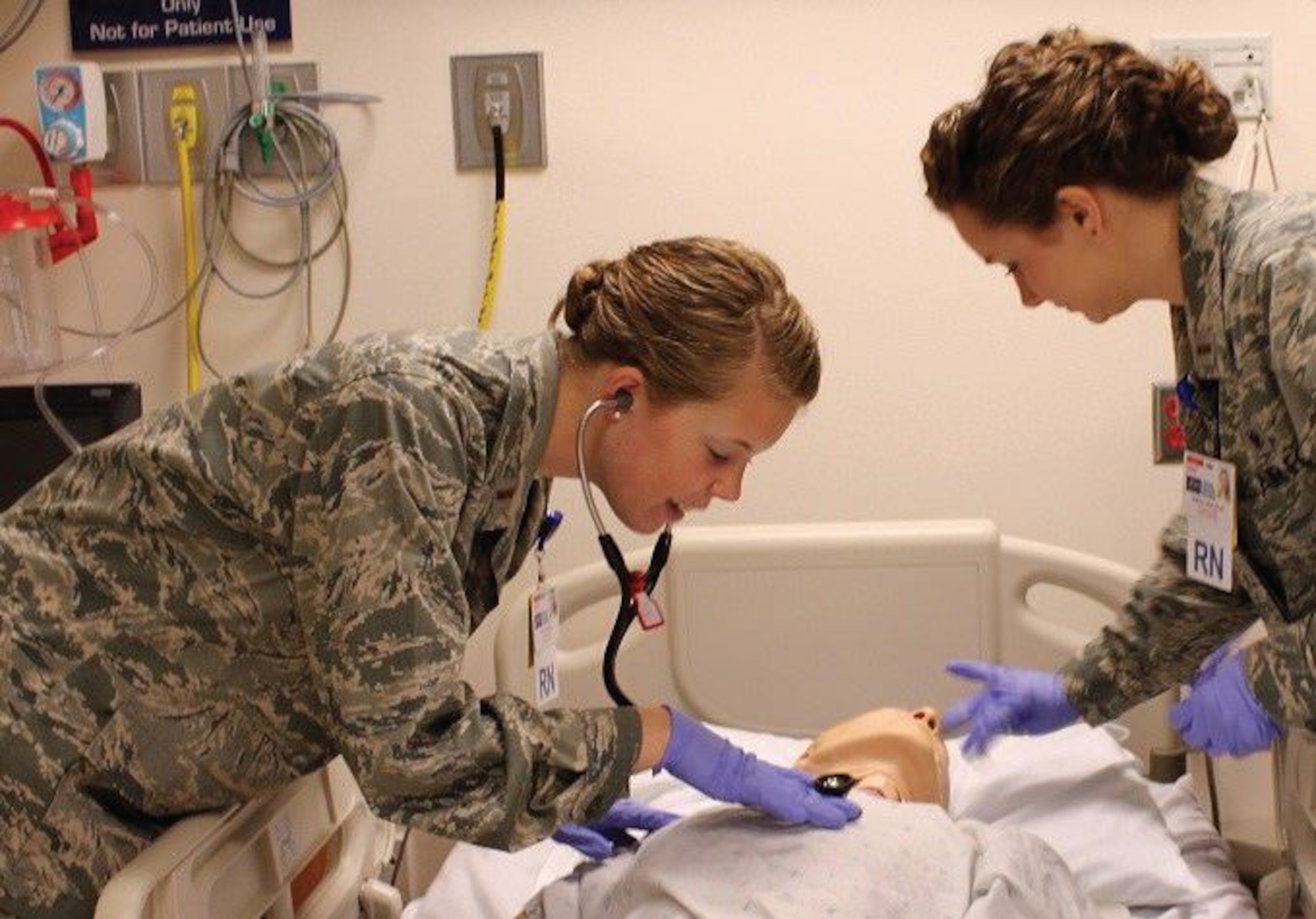 Two Air Force residency nurses practice patient care on a dummy.