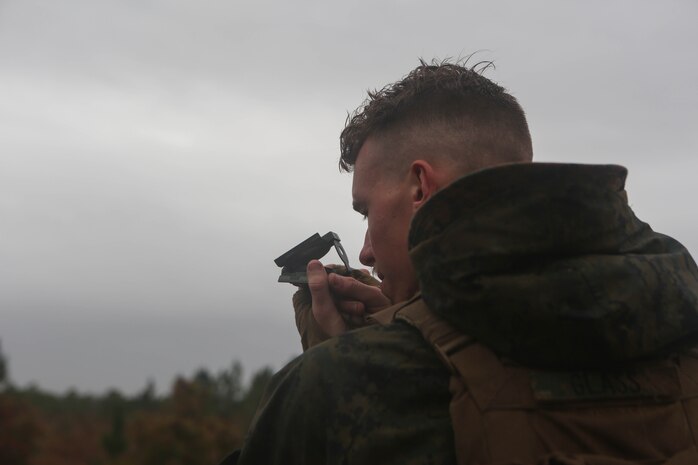 A Marine with 3rd Battalion, 6th Marine Regiment, looks a through compass during a 60mm mortar live-fire range at Marine Corps Base Camp Lejeune, N.C., Nov. 19, 2015. Despite heavy rainfall and wind, the Marines completed the mortar shoot in order to retain and refine their skills with the weapons system and prove they could complete a fire mission under any conditions. 