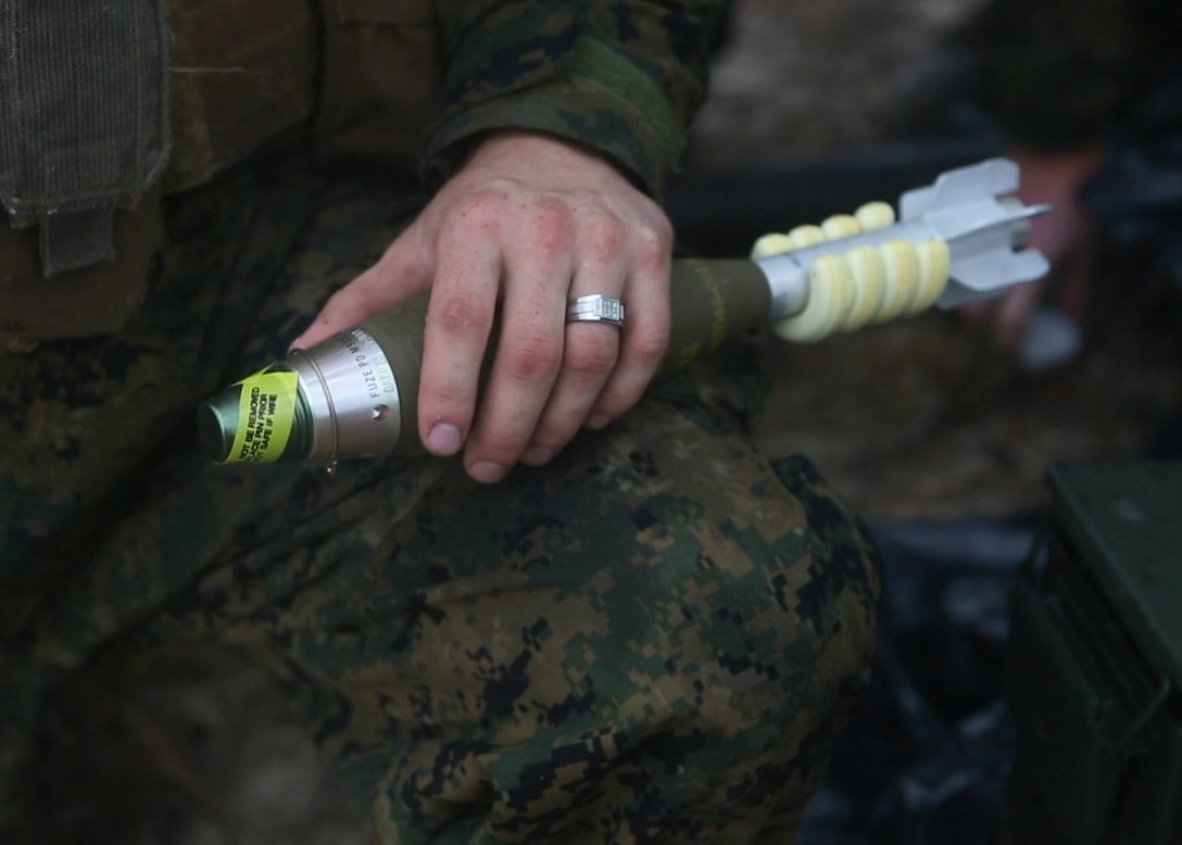 A Marine with 3rd Battalion, 6th Marine Regiment, holds a 60mm mortar round during a live-fire range at Marine Corps Base Camp Lejeune, N.C., Nov. 19. 2015. Despite heavy rainfall and wind, the Marines completed the mortar shoot in order to retain and refine their skills with the weapons system and prove they could complete a fire mission under any conditions. 