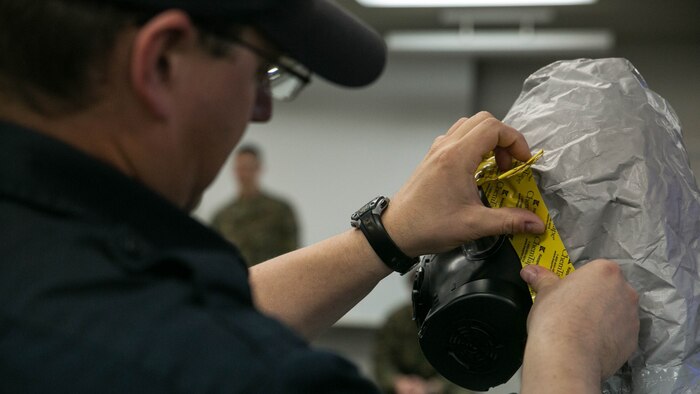 Bob Opett, a Hazardous Material Awareness and Operations course instructor, shows service members and firefighters how to properly seal the HazMat suit during the course at Marine Corps Air Station Iwakuni, Japan, Nov. 18, 2015. Provided by Bucks County Community College Department of Public Safety from Doylestown, Penn., the course is used to make individuals more aware of potential hazards and teach them initial response procedures.  