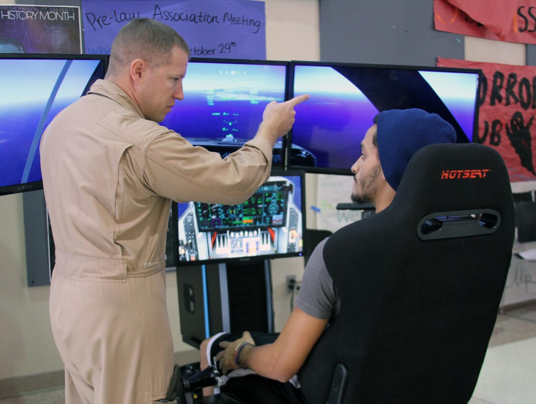 U.S. Marine Corps Capt. Richard Jacobs, the 4th Marine Corps District aviation assistant for officer procurement, instructs a student on flying the F-35B Lightning II Joint Strike Fighter simulator at Old Dominion University, Oct. 29. The simulators, part of the Marine Corps Flight Orientation Program, are used to generate interest among potential officer candidates for Marine aviation programs, and give the participants an idea of what flying the Corps’ latest fighter jet is like.