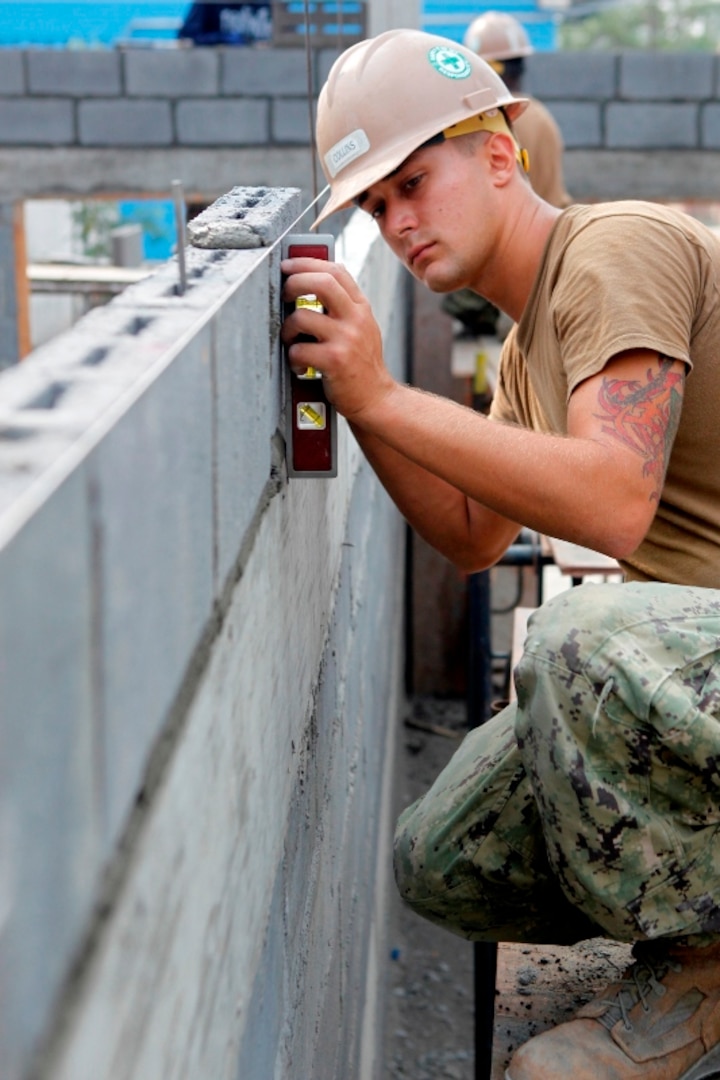 Navy Seabee Constructionman Sean Collins levels brick on a wall of a multipurpose building at the Wat Chalheamlap School in Thailand. DLA Troop Support Construction and Equipment's maintenance, repair and operations program concept was designed to integrate commodities and provide comprehensive facilities maintenance support.