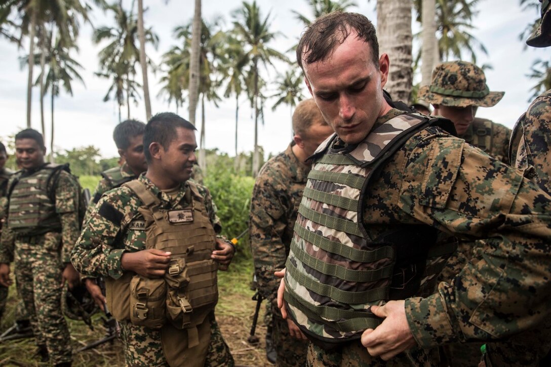 TANDUO BEACH, Malaysia (Nov. 10, 2015) U.S. Marine Lance Cpl. Joshua Cuevas dons gear from a Malaysian soldier during Malaysia-United States Amphibious Exercise 2015. Cuevas is a rifleman with Kilo Company, Battalion Landing Team 3rd Battalion, 1st Marine Regiment, 15th Marine Expeditionary Unit. During MALUS AMPHEX 15, Marines with the 15th MEU and Malaysian soldiers exchanged infantry weapon capabilities and tactics. The purpose of the exercise was to strengthen military cooperation in the planning and execution of amphibious operations between Malaysian armed forces and U.S. Marines. The 15th MEU is currently deployed in the Indo-Asia-Pacific region to promote regional stability and security in the U.S. 7th Fleet area of operations. (U.S. Marine Corps photo by Sgt. Emmanuel Ramos/Released)