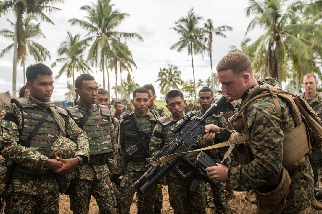 TANDUO BEACH, Malaysia (Nov. 10, 2015) U.S. Marine Lance Cpl. Nicolas Biglione demonstrates speed reloads to Malaysian soldiers during Malaysia-United States Amphibious Exercise 2015. Biglione is a machine gunner with Kilo Company, Battalion Landing Team 3rd Battalion, 1st Marine Regiment, 15th Marine Expeditionary Unit. During MALUS AMPHEX 15, Marines with the 15th MEU and Malaysian soldiers exchanged infantry weapon capabilities and tactics. The purpose of the exercise was to strengthen military cooperation in the planning and execution of amphibious operations between Malaysian armed forces and U.S. Marines. The 15th MEU is currently deployed in the Indo-Asia-Pacific region to promote regional stability and security in the U.S. 7th Fleet area of operations. (U.S. Marine Corps photo by Sgt. Emmanuel Ramos/Released)