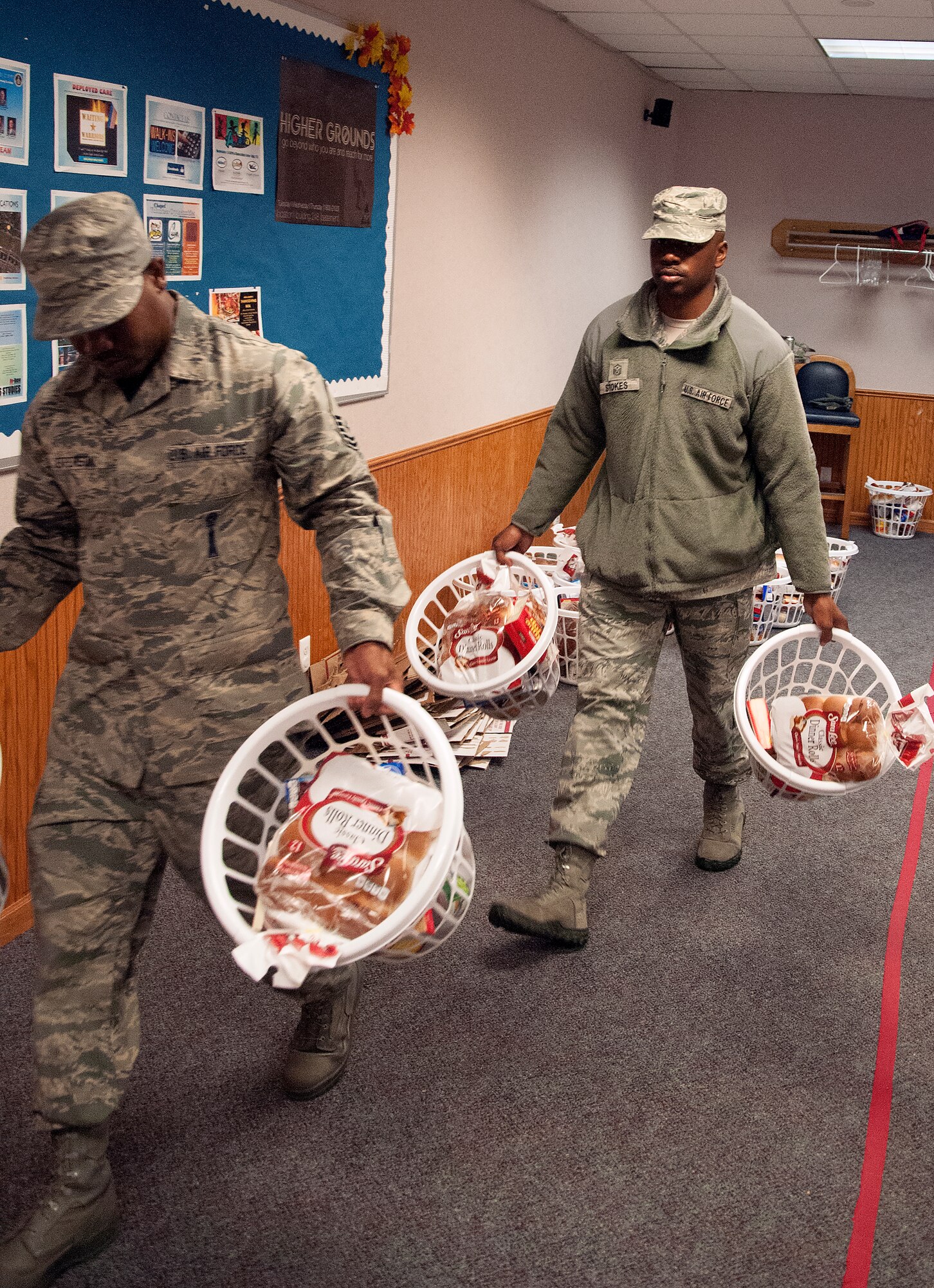 Master Sgt. Christopher Stokes, 90th Munitions Squadron first sergeant, and another volunteer carry baskets full of Thanksgiving items out of the Chapel Activity Center on F.E. Warren Air Force Base, Wyo. Nov. 20, 2015. Each basket contained the ingredients to make a Thanksgiving meal, including rolls, corn and cranberries. (U.S. Air Force photo by Airman 1st Class Brandon Valle)