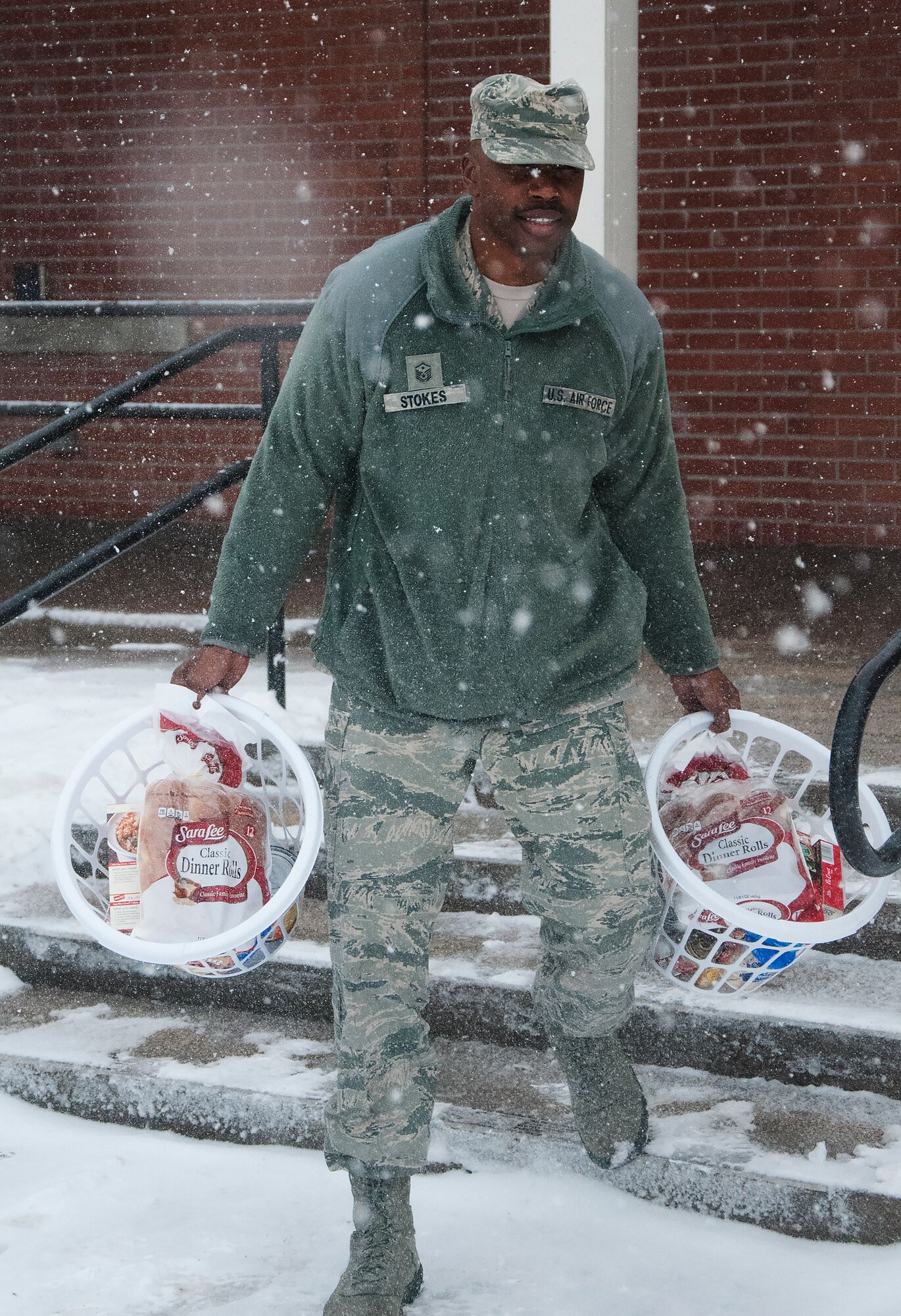 Master Sgt. Christopher Stokes, 90th Munitions Squadron first sergeant, braves snowy weather to carry Thanksgiving baskets to his car Nov. 20, 2015, after the First Sergeants Council made the baskets inside the Chapel Activity Center on F.E. Warren Air Force Base, Wyo. Squadron first sergeants came together to make baskets for Airmen who needed a little assistance during the holidays. (U.S. Air Force photo by Airman 1st Class Brandon Valle)