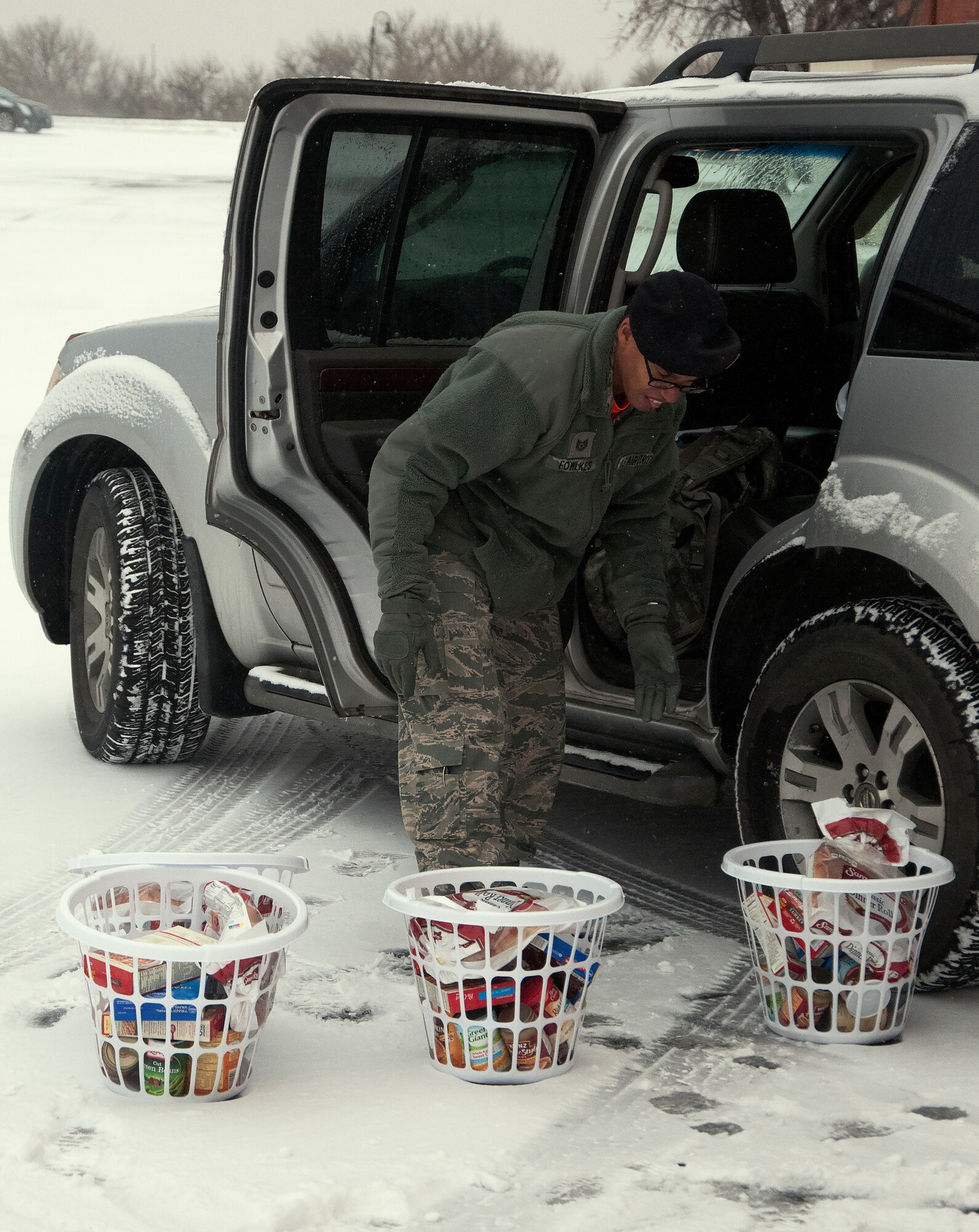 Tech. Sgt. Jefferey Fowlkes, 90th Security Support Squadron Operations Support NCO in-charge, reaches down to grab a Thanksgiving basket to put into his car Nov. 20, 2015. The Fowlkes helped the F.E. Warren first sergeants association make 125 baskets and delivered them to the Airmen while they worked, surprising them before the weekend. (U.S. Air Force photo by Airman 1st Class Brandon Valle)