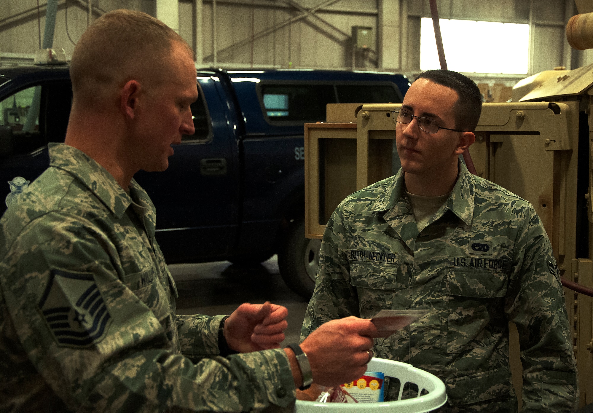 Master Sgt. Brian Williams, 90th Logistics Readiness Squadron, presents Airman 1st Class Jason Barth-Heckler, with a Thanksgiving basket Nov. 20, 2015, inside the LRS vehicle maintenance bay on F.E. Warren Air Force Base, Wyo. Airmen were selected by their leadership to receive the baskets as a way to help out during the holidays. (U.S. Air Force photo by Airman 1st Class Brandon Valle)