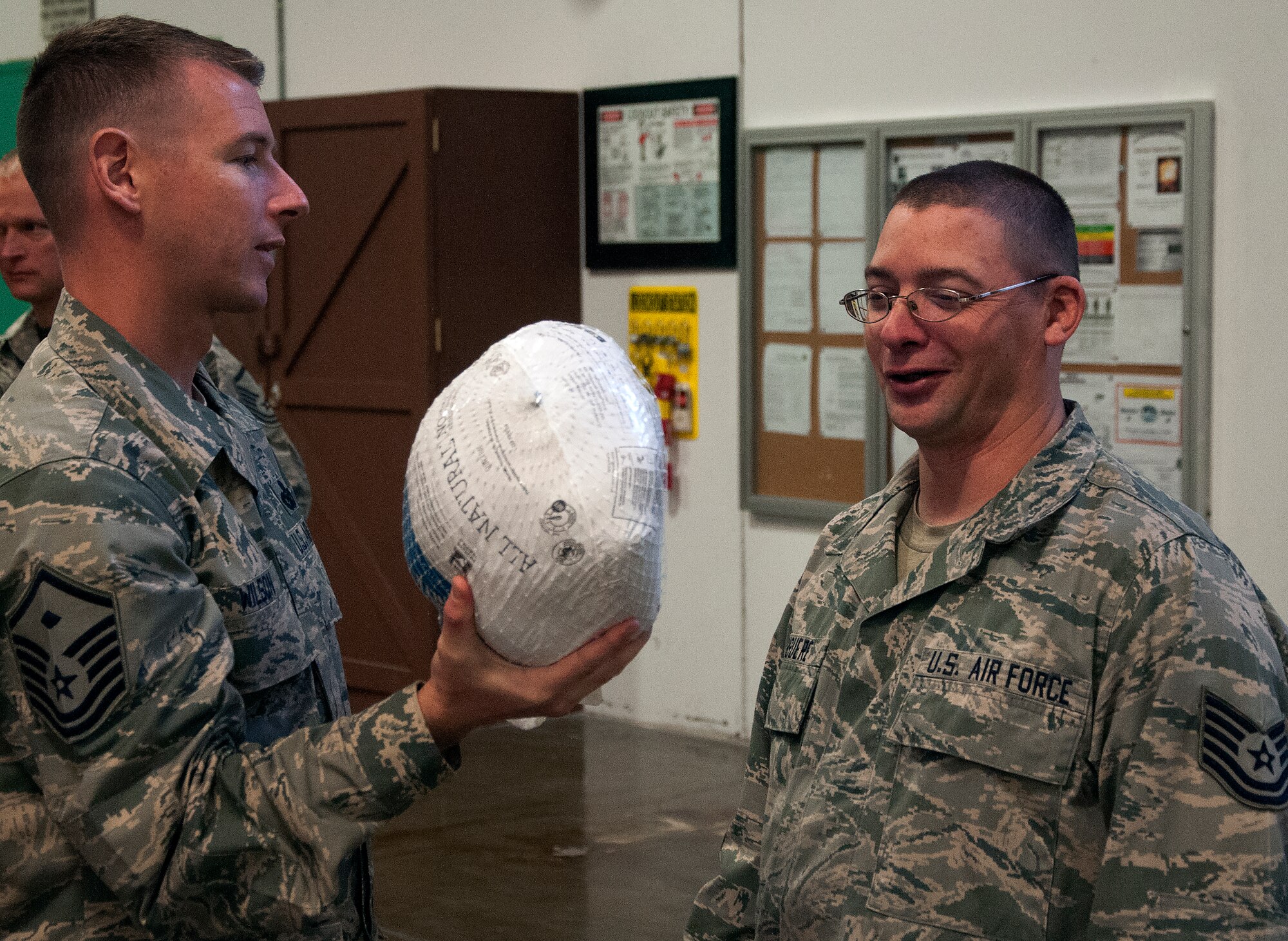 Master Sgt. Robert Wilson, 90th Logistics Readiness Squadron first sergeant, presents Tech. Sgt. Jason Giguere, 90th LRS, with a frozen turkey inside the LRS warehouse Nov. 20, 2015, to be used for Thanksgiving dinner. Turkeys were donated by a local vendor to be handed out to Airmen. (U.S. Air Force photo by Airman 1st Class Brandon Valle)