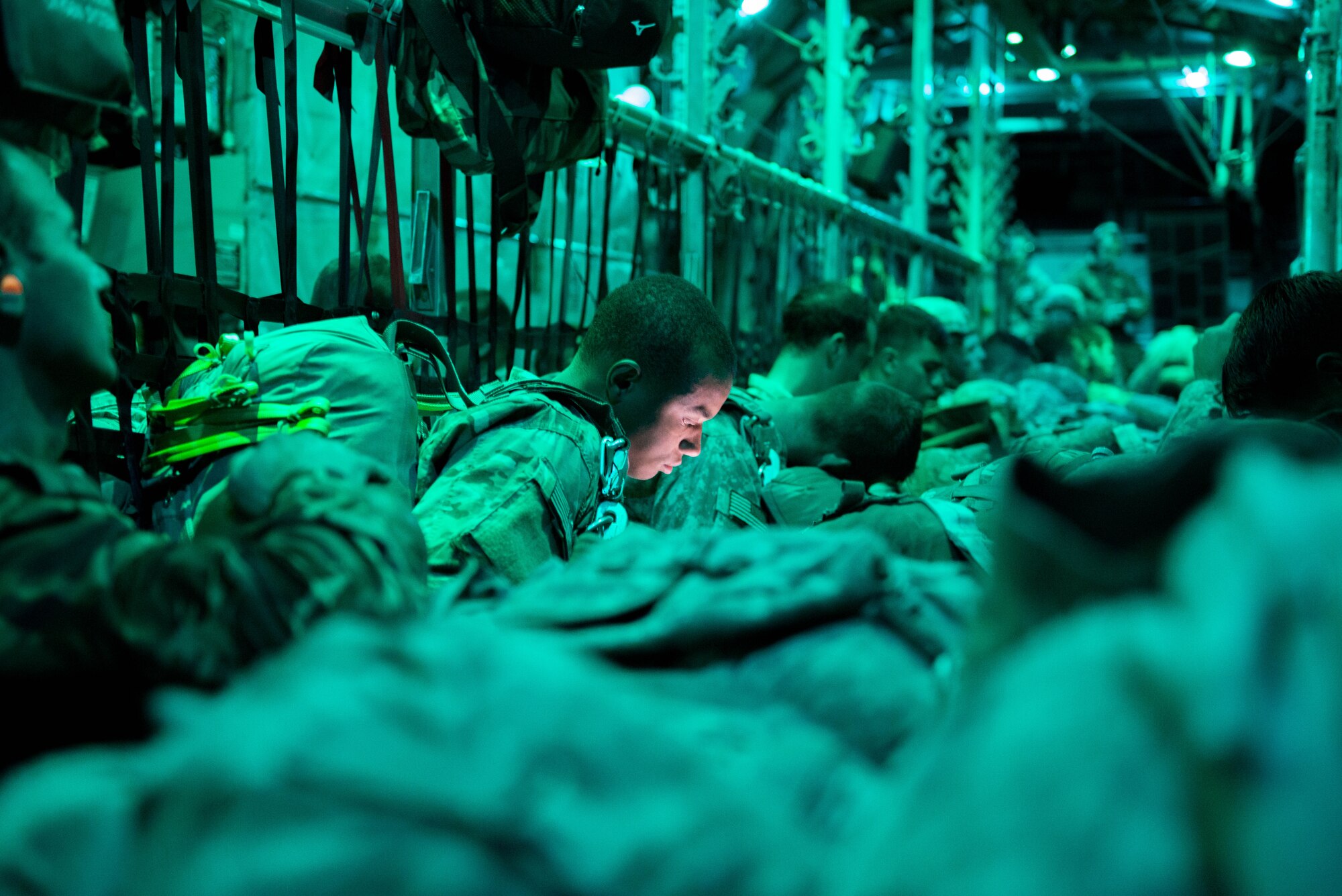 An army paratrooper uses his phone as he sits in a C-130, preparing to jump during a night jump as a part of exercise Swift Response. (U.S. Air Force photo by Staff Sgt. Trevor Saylor/Released)